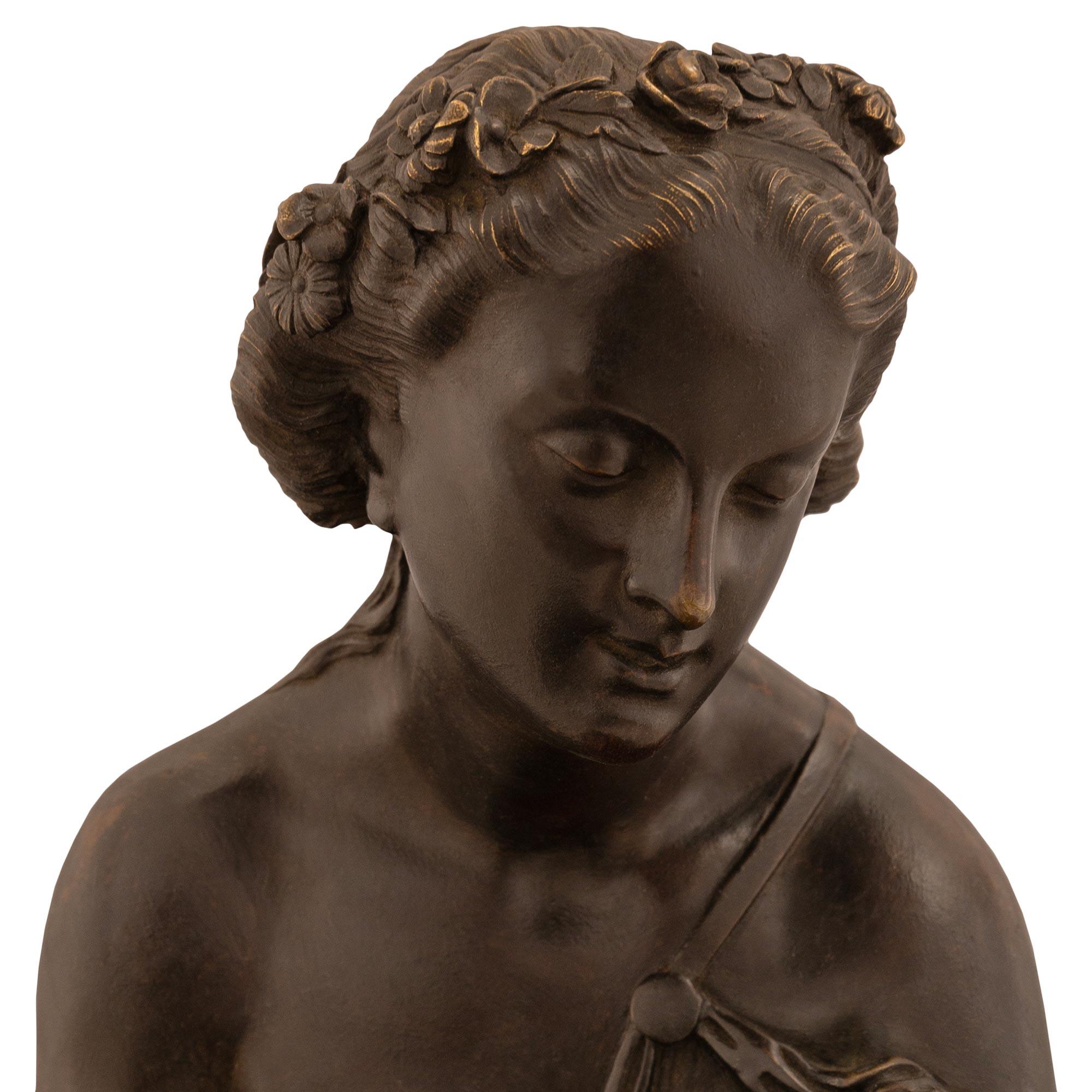 A French 19th century patinated Bronze and black Belgian marble statue signed by Schoenewerk and Marchand. The statue is raised on an oval Black Belgium marble base with double mottled edge top. Above is a young maiden wearing a classical dress