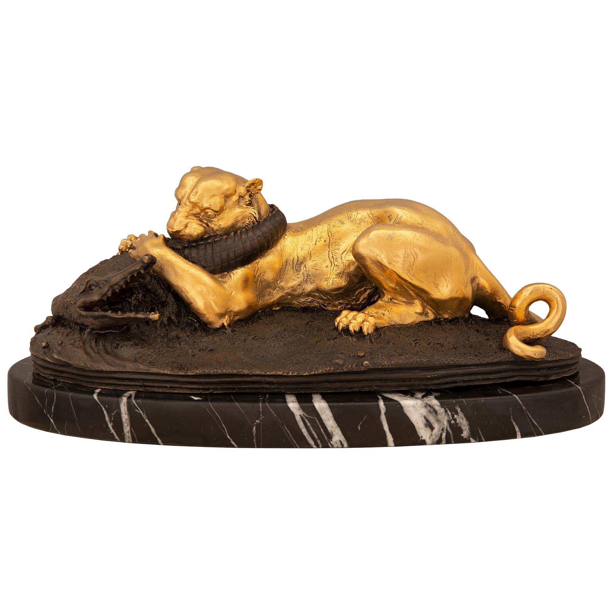 Superbe statue française du XIXe siècle en bronze patiné et bronze doré représentant une panthère mangeant un alligator, signée par Jules Moigniez. La statue est élevée sur une base oblongue avec un dessin au sol merveilleusement exécuté. La