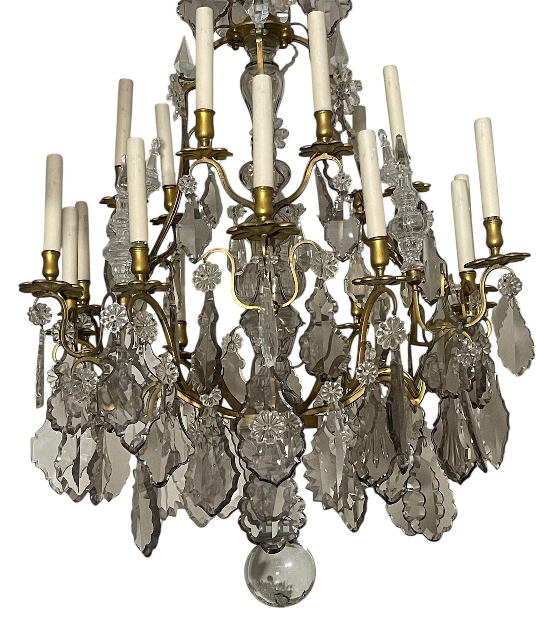 Grande lampadario francese in bronzo del XIX secolo ornato da abbondanti vetri tagliati chiari e fumé alla maniera di Baccarat. La cornice in bronzo, ricca di dettagli, è decorata con prismi sfaccettati, pendenti e rosette che creano un drammatico