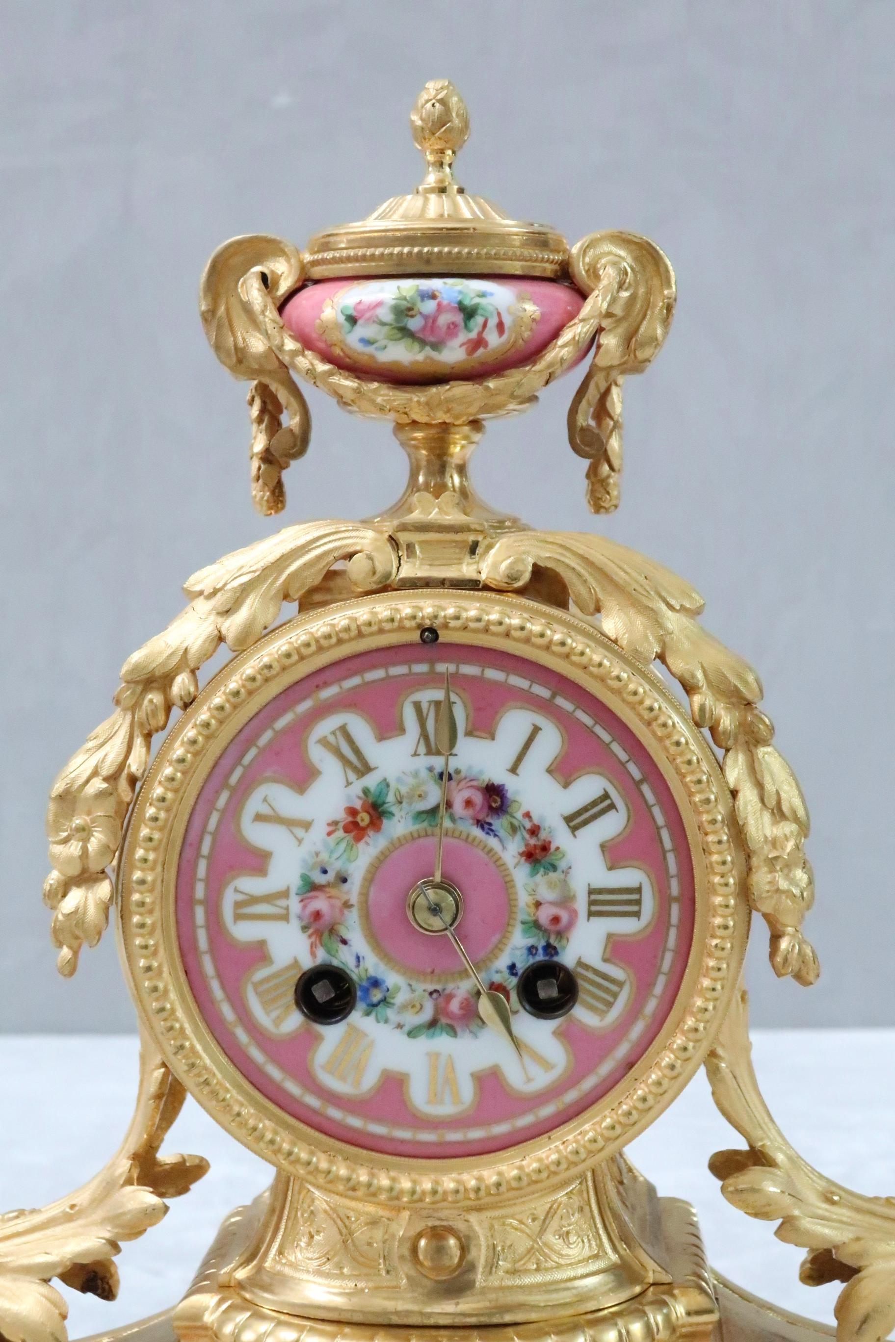 An extremely fine and decorative French bronze gilt mantel clock with scrolling foliate design throughout, pink sevre style painted porcelain panels finished with urn to the top stood on a shaped gilded wooden base. The clock has an eight day French
