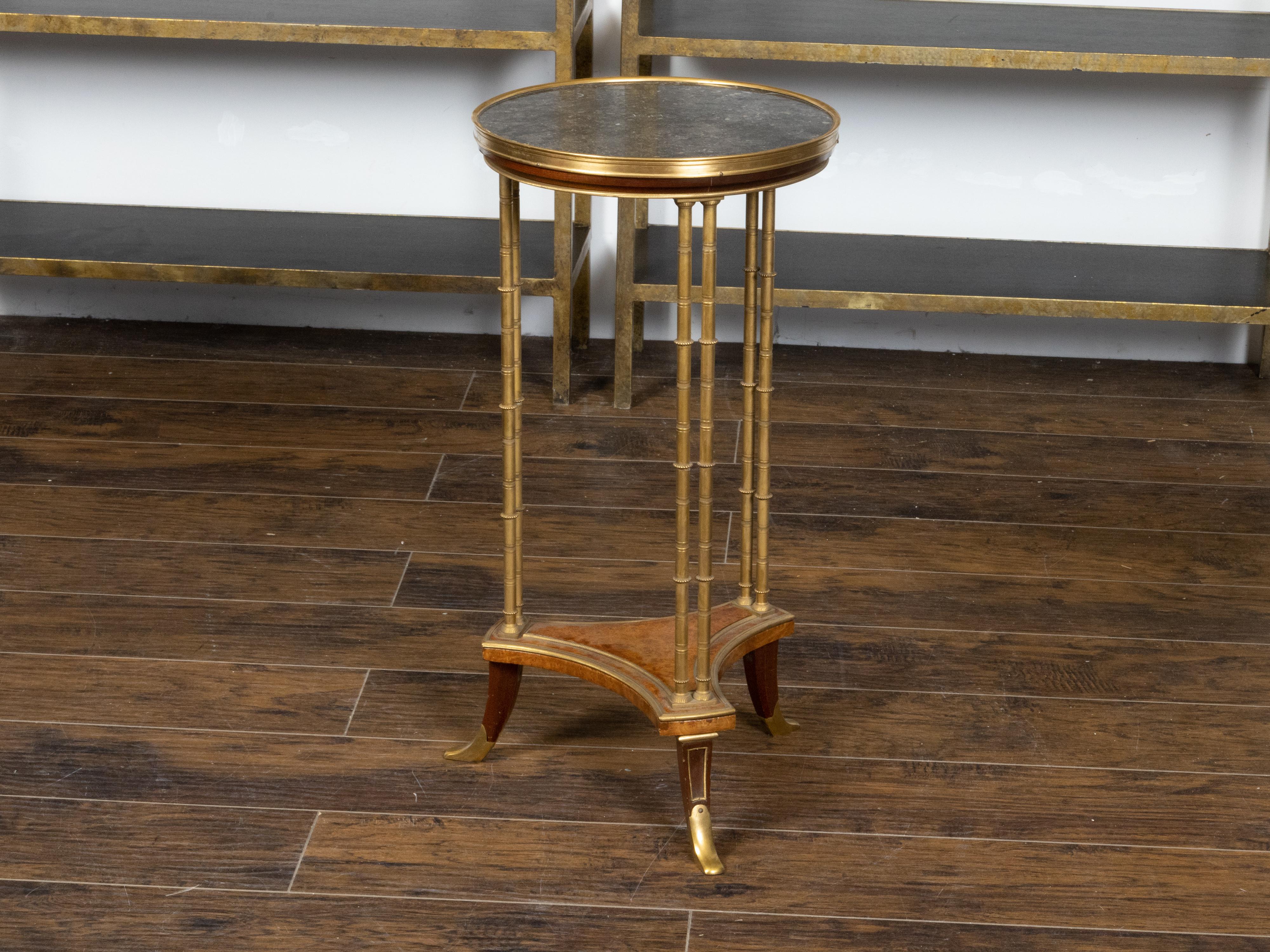 A French bronze guéridon side table from the 19th century with black marble top, faux bamboo legs and burl shelf. Created in France during the 19th century, this bronze guéridon side table features a circular black marble top sitting above a faux