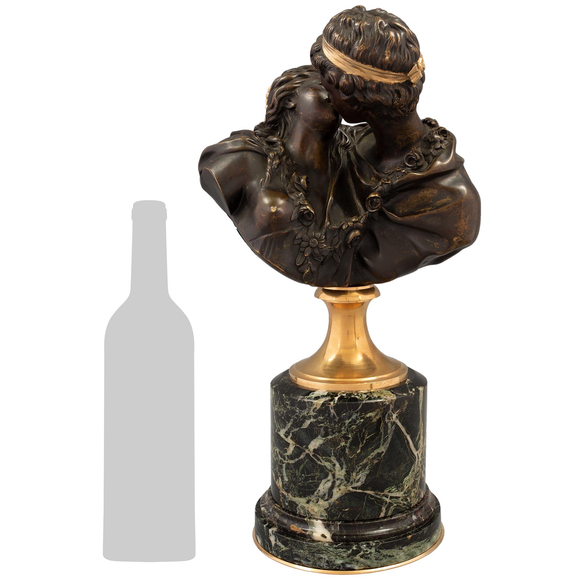 A charming and high quality French 19th century patinated Bronze, Ormolu and Vert Antique Grec marble bust of Le Baiser Donné, modeled after Jean Antoine Houdon. This most elegant bust is raised by a circular stepped Vert Antique Grec marble base