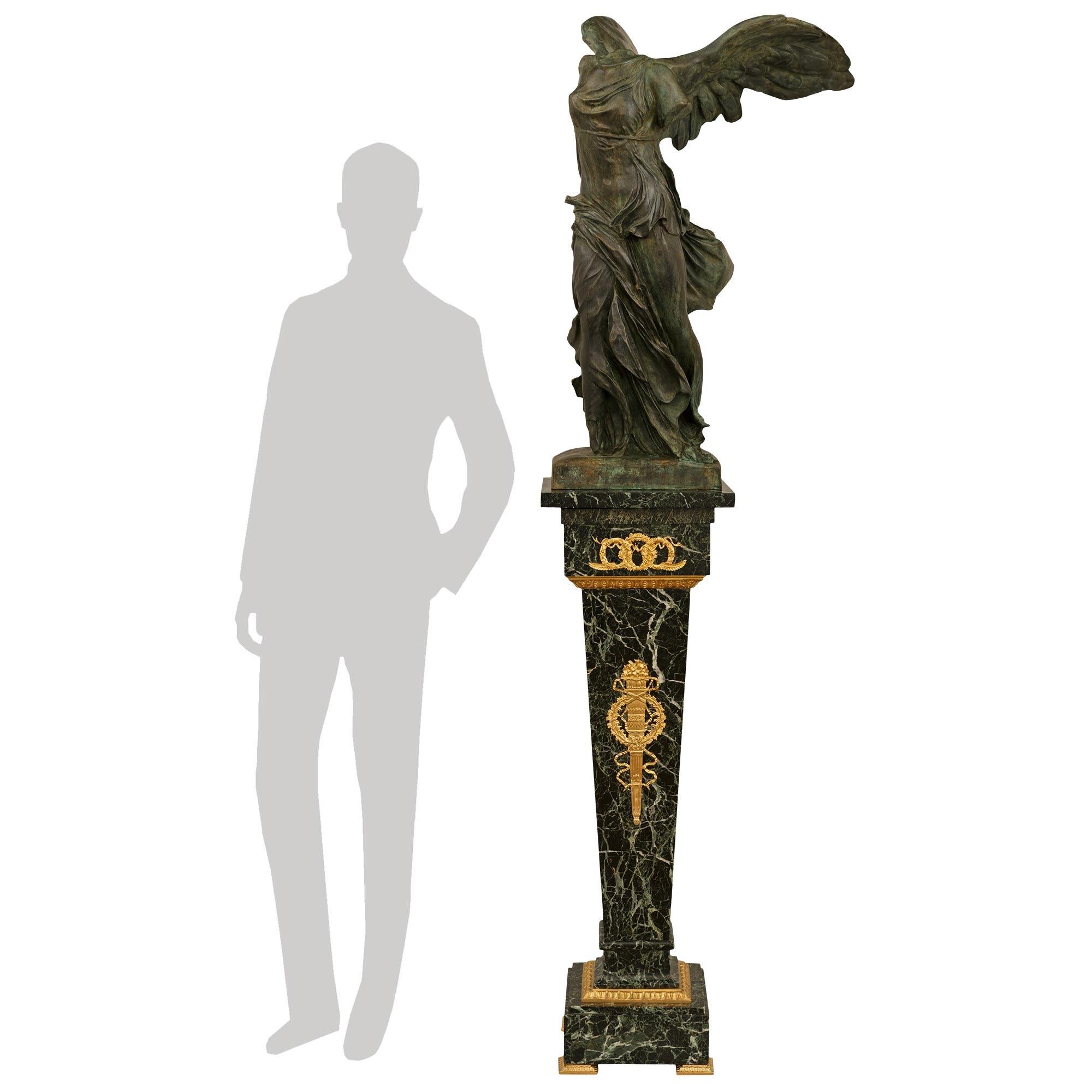 Splendida statua in bronzo verdastro, ormolu e marmo del XIX secolo della Vittoria alata di Samotracia. Questa splendida statua poggia su un piedistallo in marmo Vert de Patricia sostenuto da alzate angolari in Ormolu con un disegno Rais de Coeur.