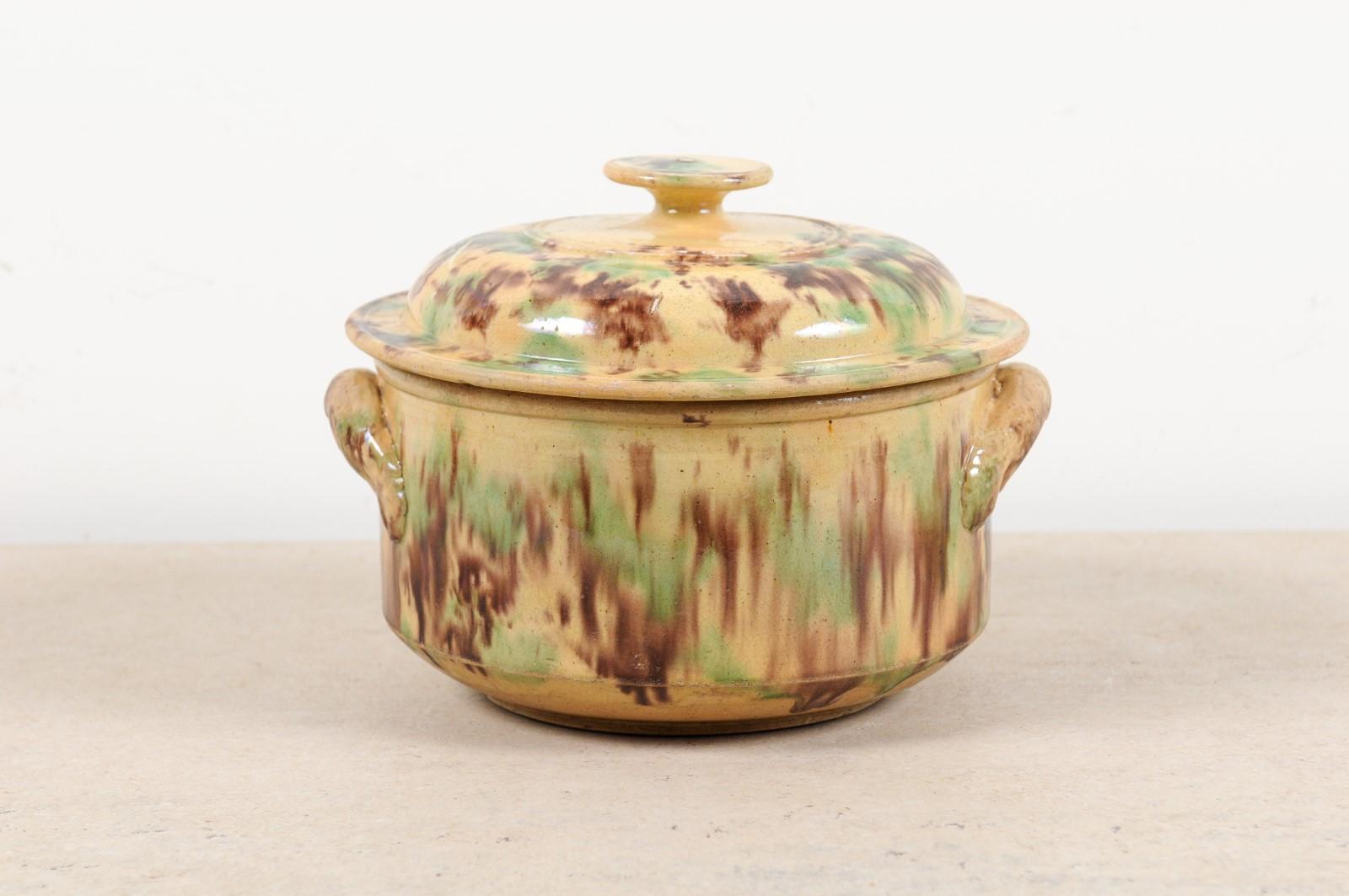 A French glazed ceramic casserole dish from the 19th century, with lid and handles. Charming us with its brown and green glaze that seems to be melting along the sides of its simple body, this casserole dish showcases a circular lid resting upon a