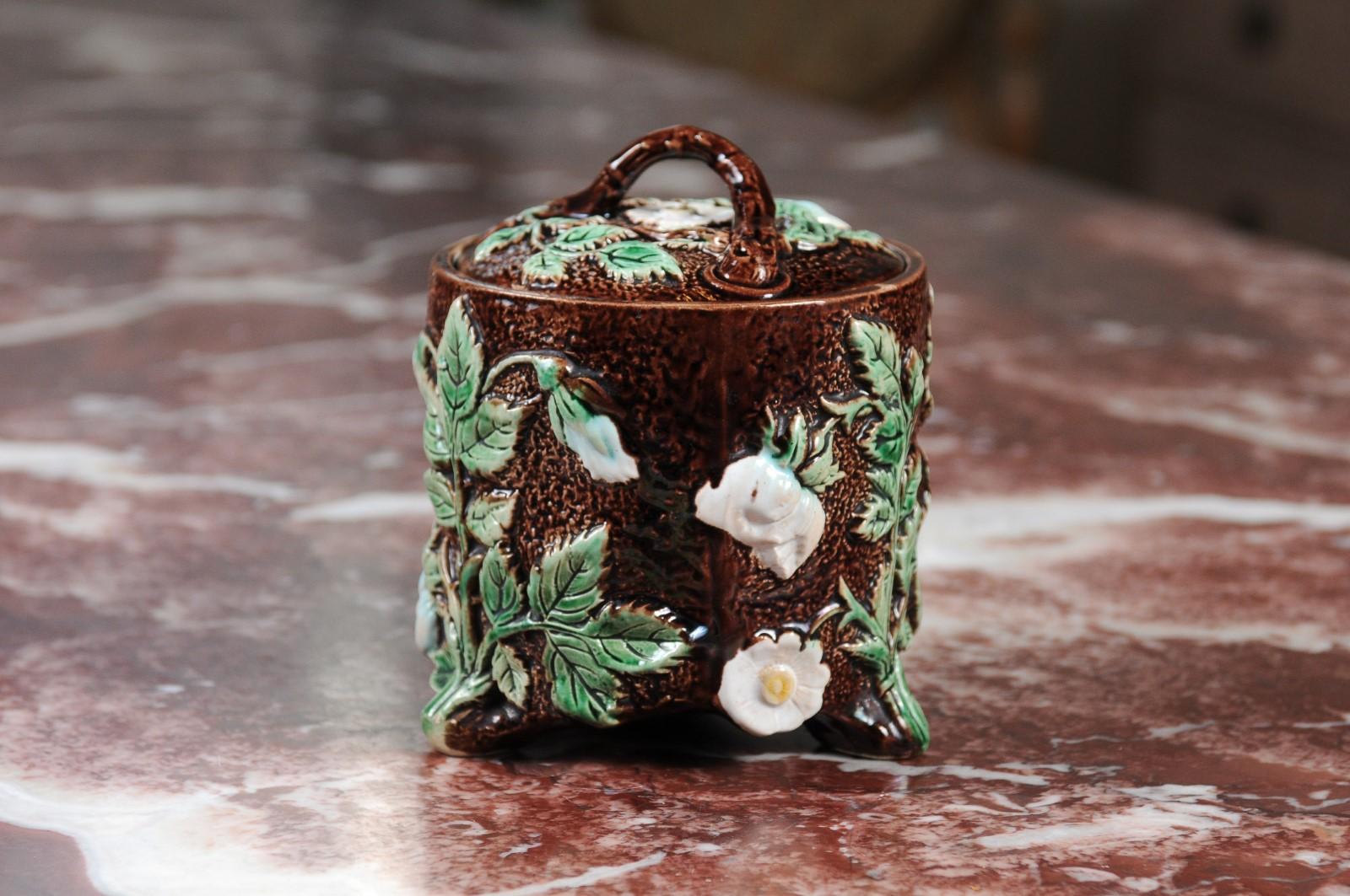 A French brown Majolica lidded jar from the 19th century with green and white moulded floral décor. Born in France during the 19th century, this Majolica jar boasts a lovely brown ground adorned with delicately molded flowers of white color,