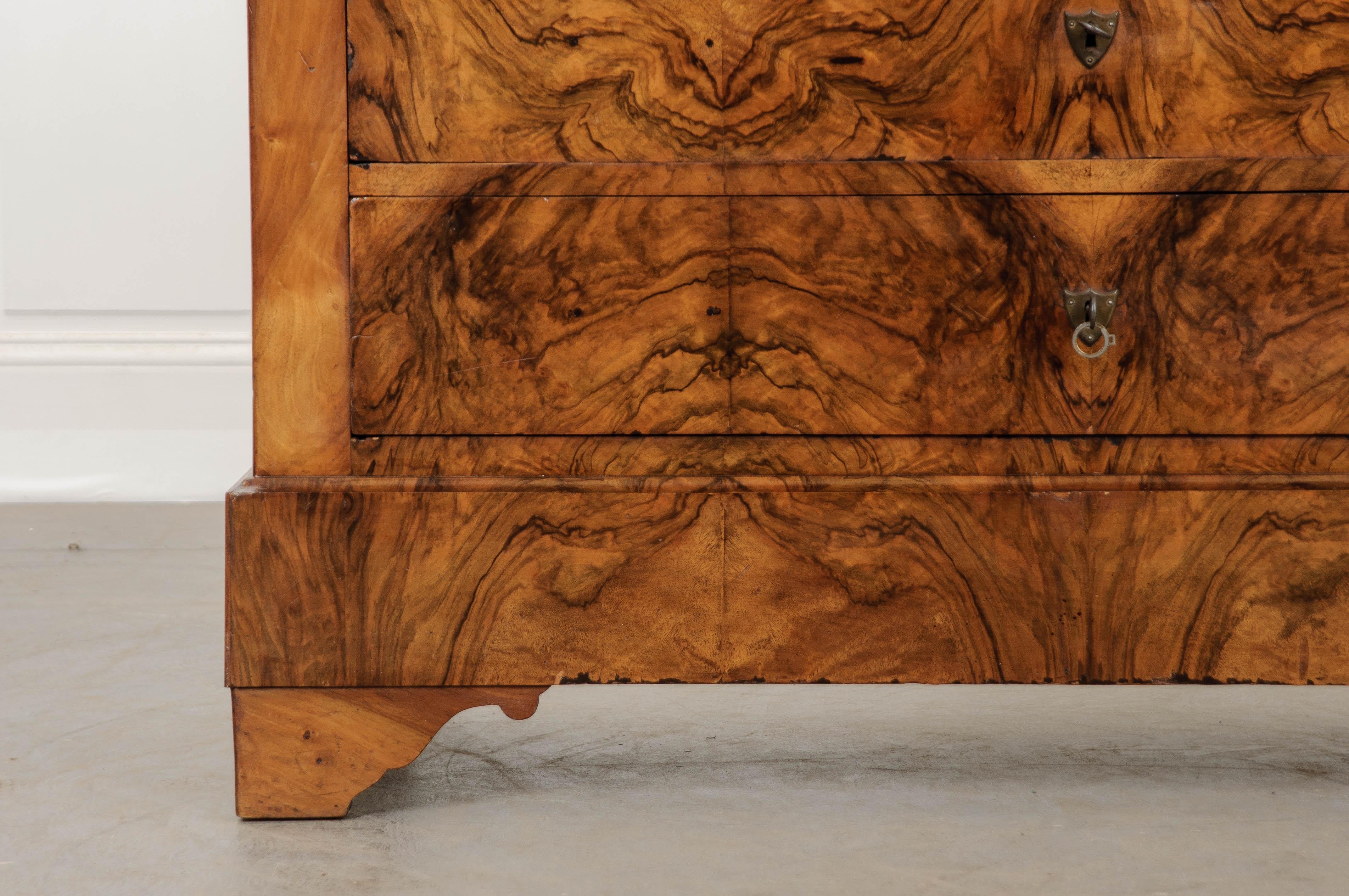 Beautifully book matched burl walnut veneer was mindfully selected when creating this exceptional four-drawer Louis Philippe style commode from 19th century France. This wonderful burl is actually caused by the knots, gnarls and deformities that are