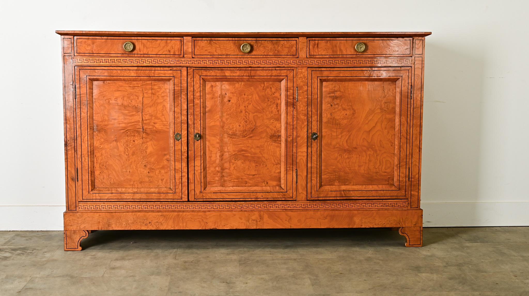 A stunning French enfilade in burl maple with Neoclassical sensibility. The exterior of the cabinetry appears glowing from the translucent, sinuous wood grain. A pinstripe border of ebonized inlay on the top creates definition around the rippled,