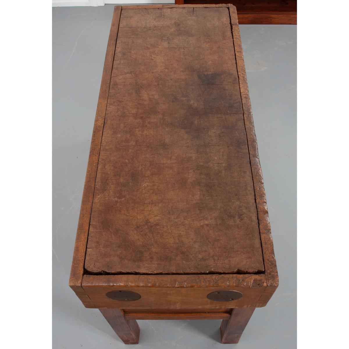 A fine butcher block table, made in France, circa 1880. The table’s top boasts exceptional patination. Grooves have been left from decades of knife work and butchery. The top has dovetail joinery at the corners and iron reinforcements to keep the