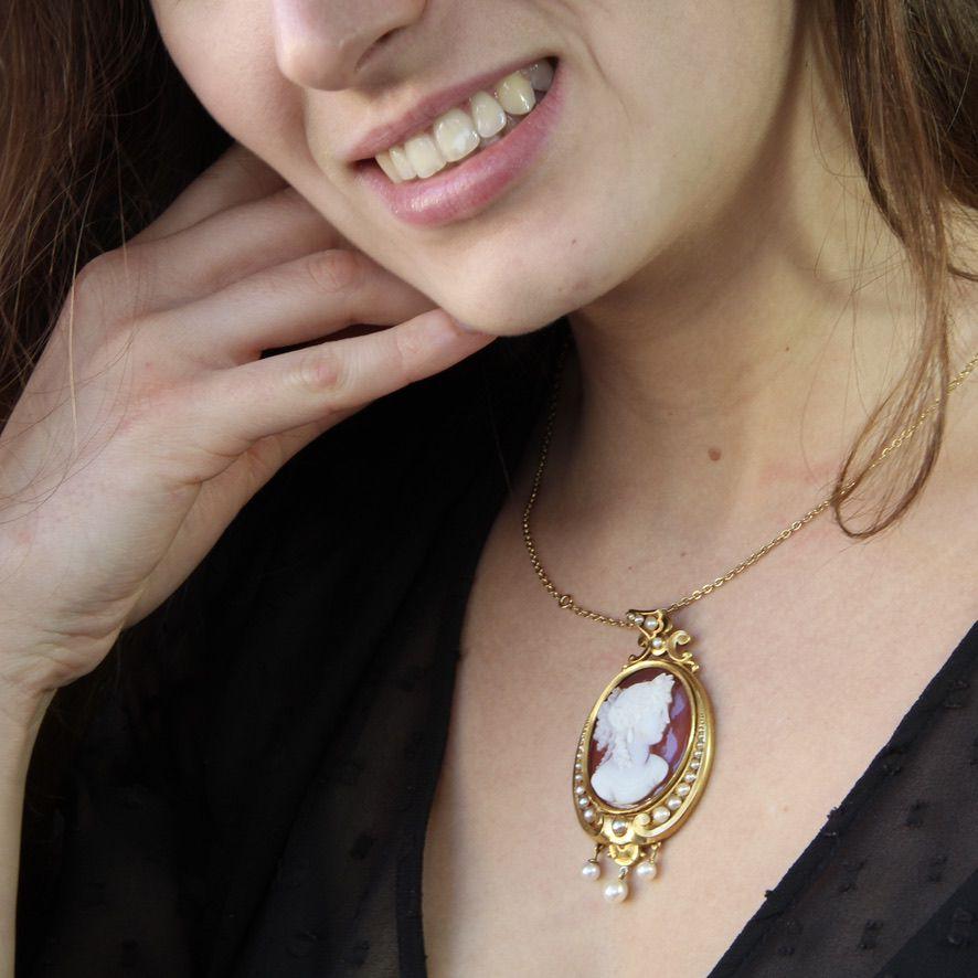 Pendant in 18 karat yellow gold.
Superb antique cameo of an elegant engraved on chalcedony, it is set on a satin yellow gold pendant set with a fall of half natural pearls on both sides. 3 natural pearls are hanging in pendants. The thick belly is