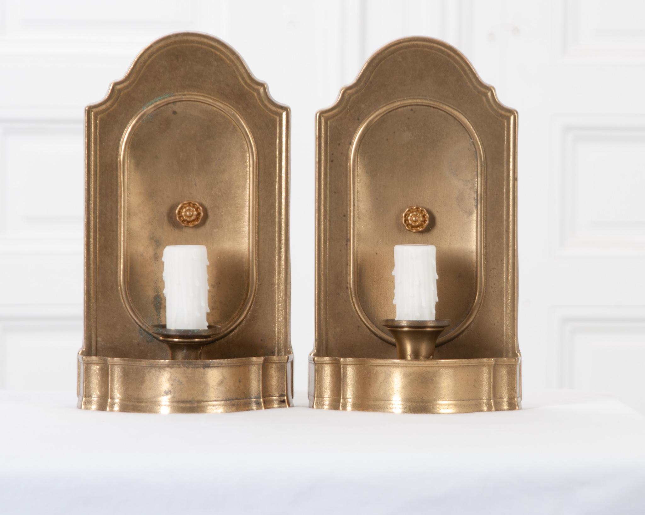 A refined pair of electrified candle sconce from 19th century France. The brass has gained a delightful patina over the years without taking away from the impressive luster. A small but detailed rosette is featured in the center of the sconce, which
