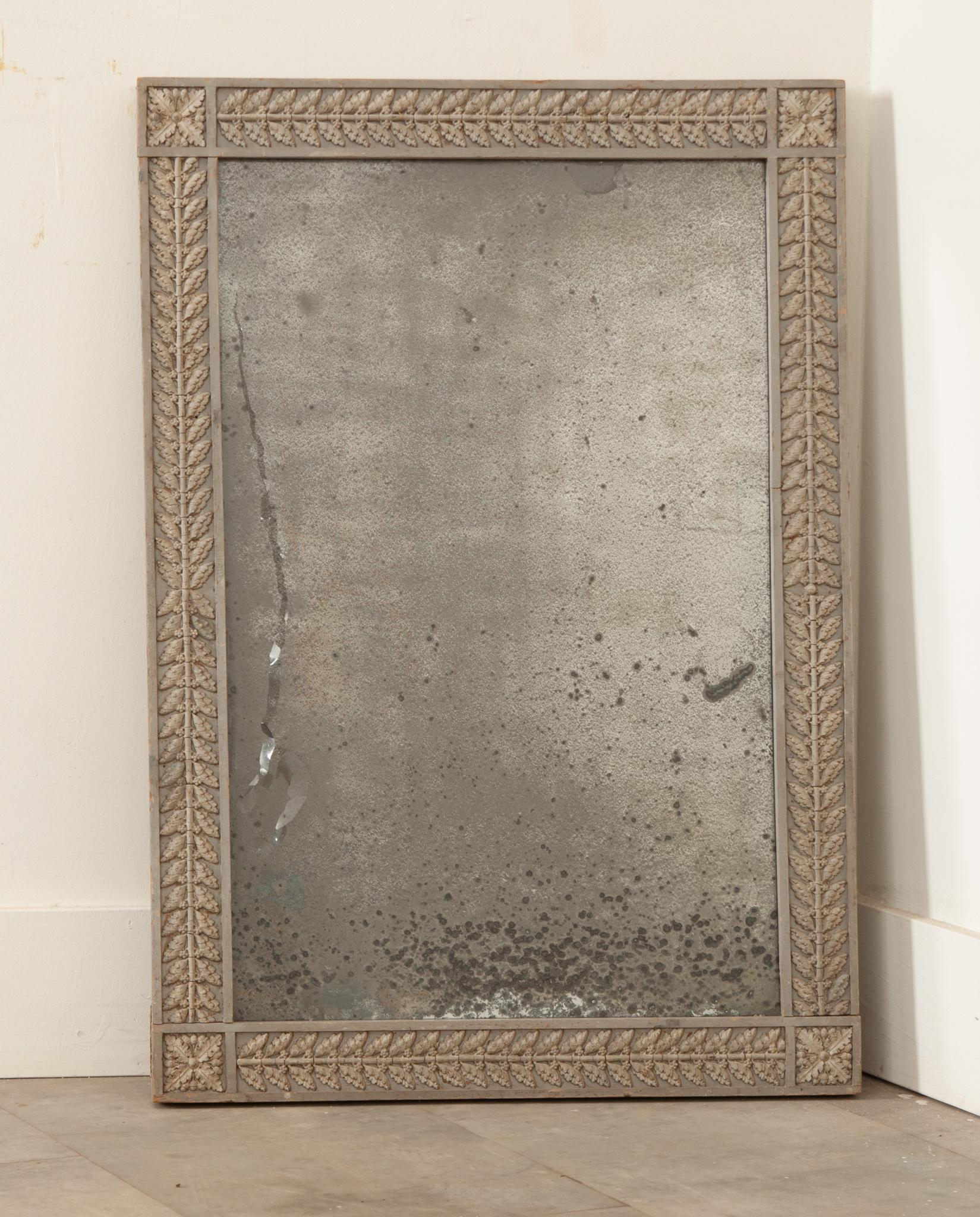 A French 19th century antique mirror in a hand-carved and painted frame with its original highly foxed mirror plate that shimmers with diamond dust. Hand-crafted in France circa 1850, this mirror features a thick, symmetrical rectangular shaped