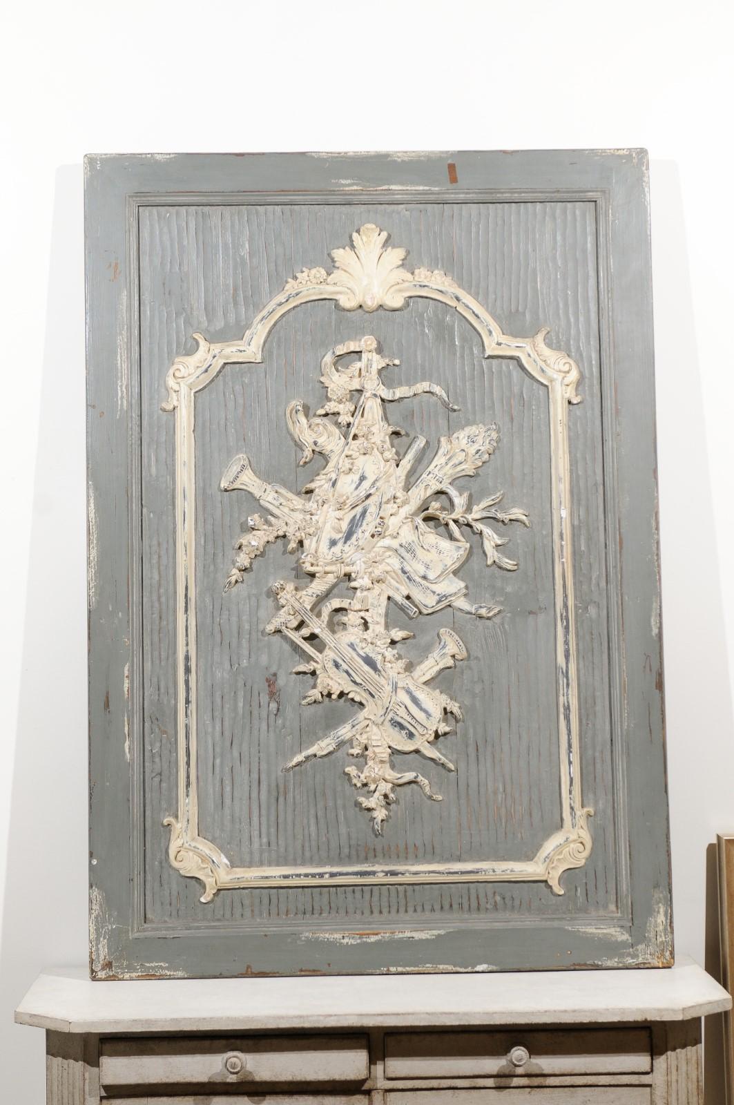A French carved and painted wooden panel from the 19th century, with musical instruments. Created in France during the 19th century, this architectural panel features a grey painted textured ground adorned with a carved Allegory of the Liberal Arts