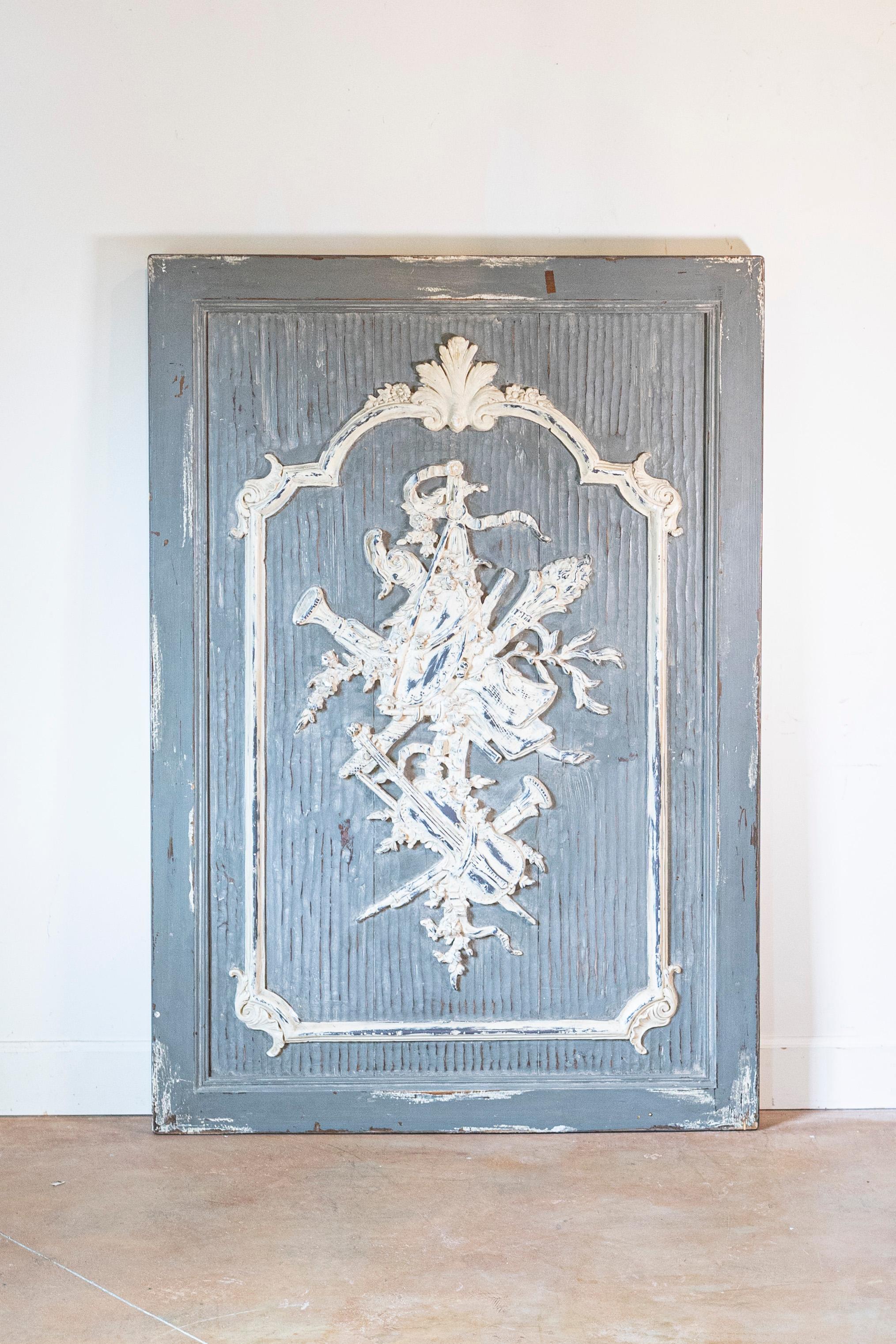 Pannello francese in legno intagliato e dipinto del XIX secolo, con strumenti musicali. Realizzato in Francia durante il XIX secolo, questo pannello architettonico presenta un fondo grigio dipinto e strutturato, ornato da un'Allegoria delle Arti