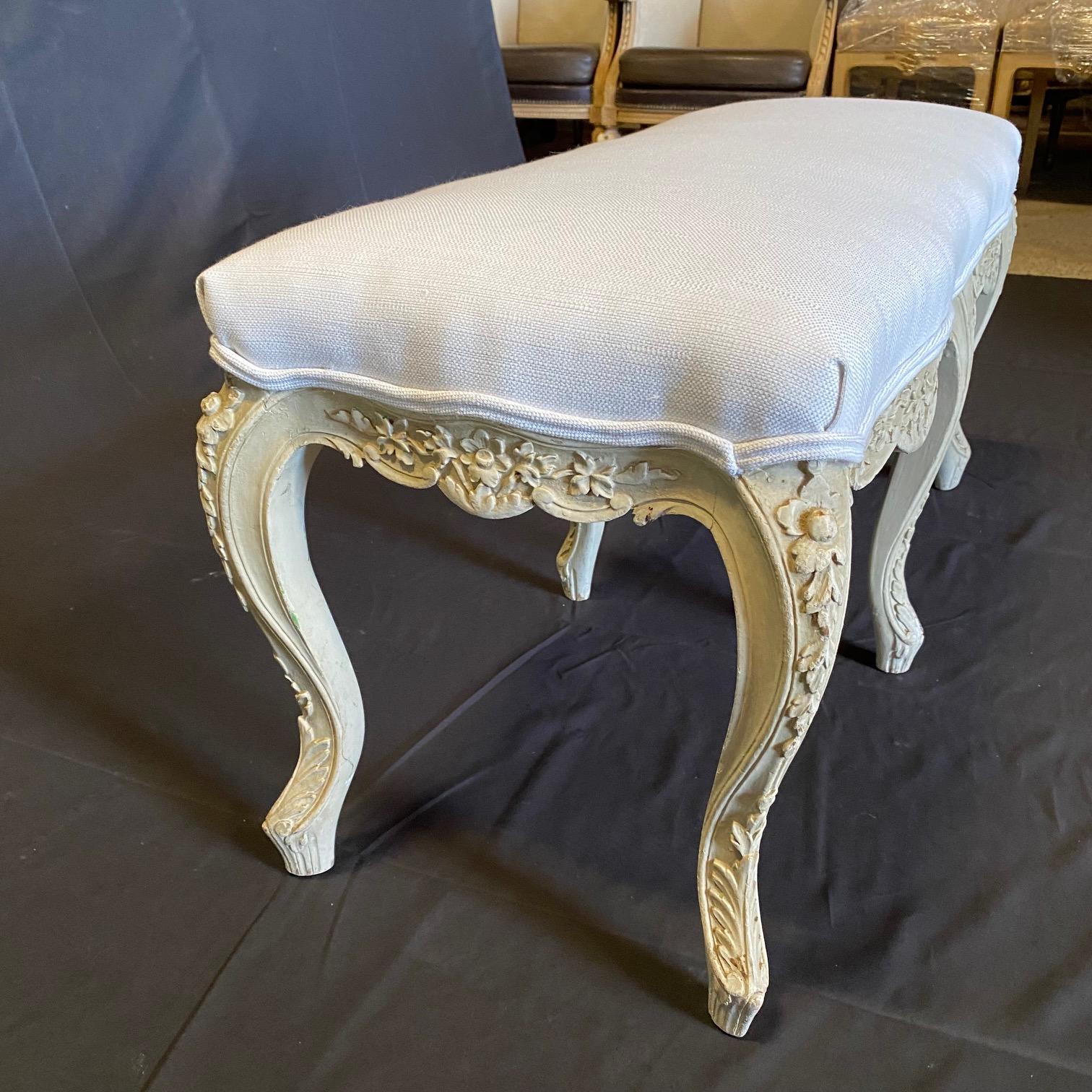 Bought in the South of France, this beautifully carved Louis XV bench retains its original lovely patinated pale white paint with a grayish patina. This elegant French Louis XV style carved bench or window bench is made of the highest quality, and