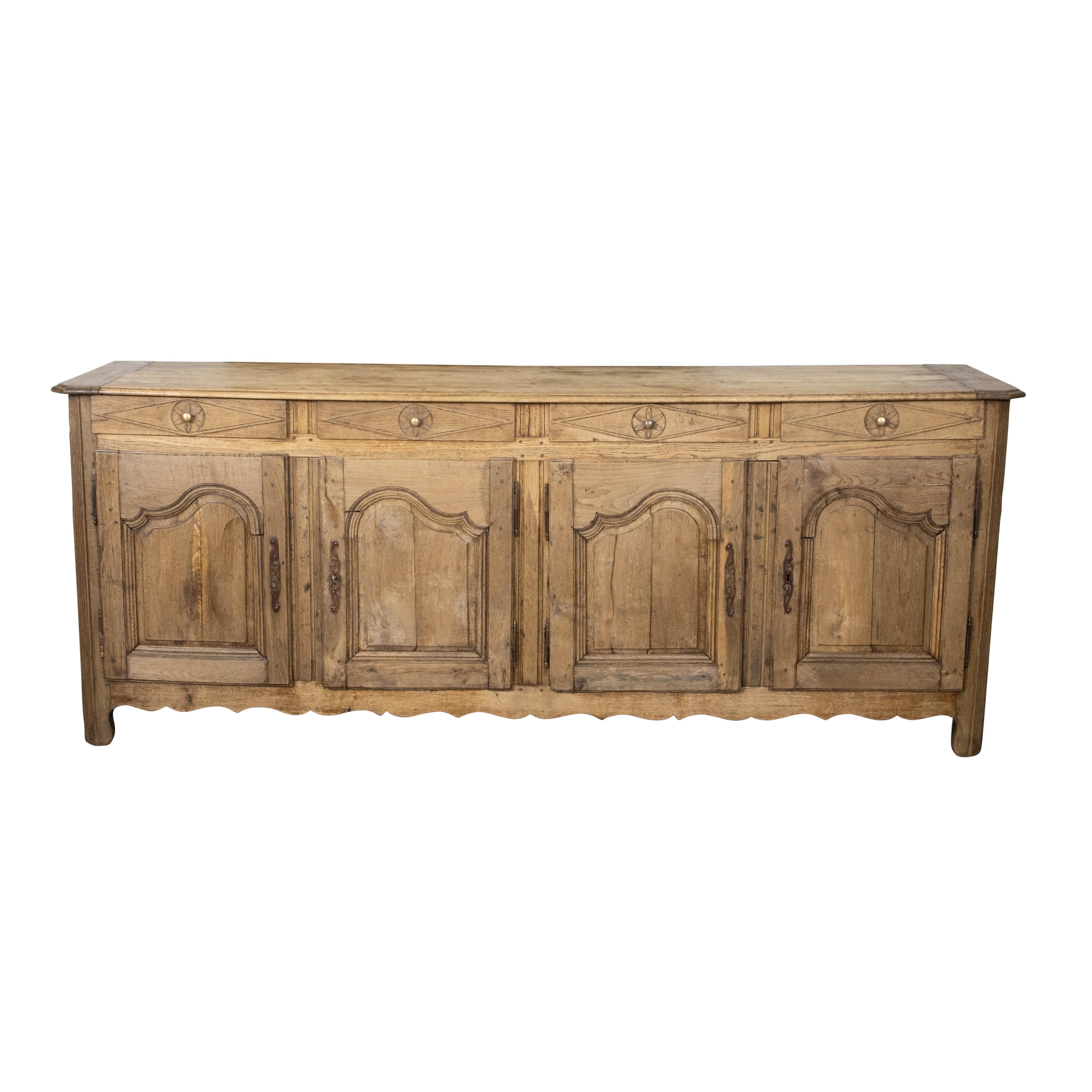 A French walnut enfilade from the 19th century with four drawers over four doors, carved motifs, scrolling feet and natural distressed patina. Charming us with its great proportions and rustic character, this walnut enfilade was created in France