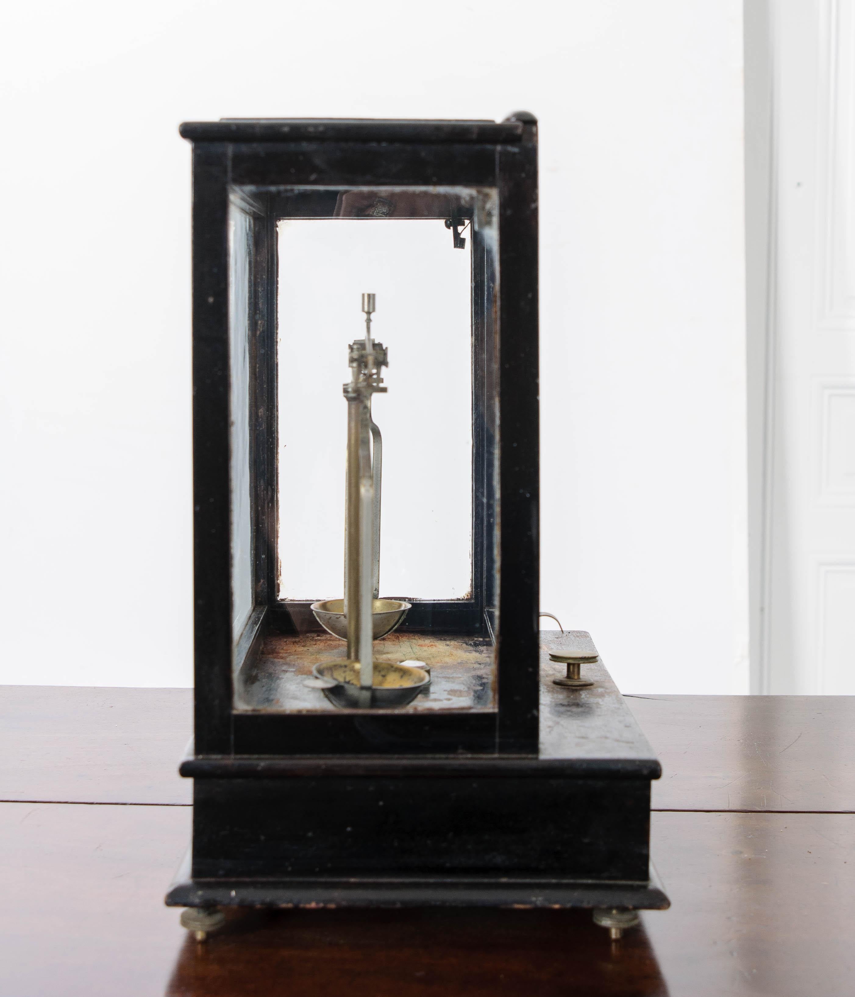 This unique French apothecary scale sits in a ebonized wood and glass case. The front of the case lifts for access to the delicate brass scale. At the base of the scale is an address etched into the plate: ‘G. Viollet 48 Rue La Fayette Paris.’ The