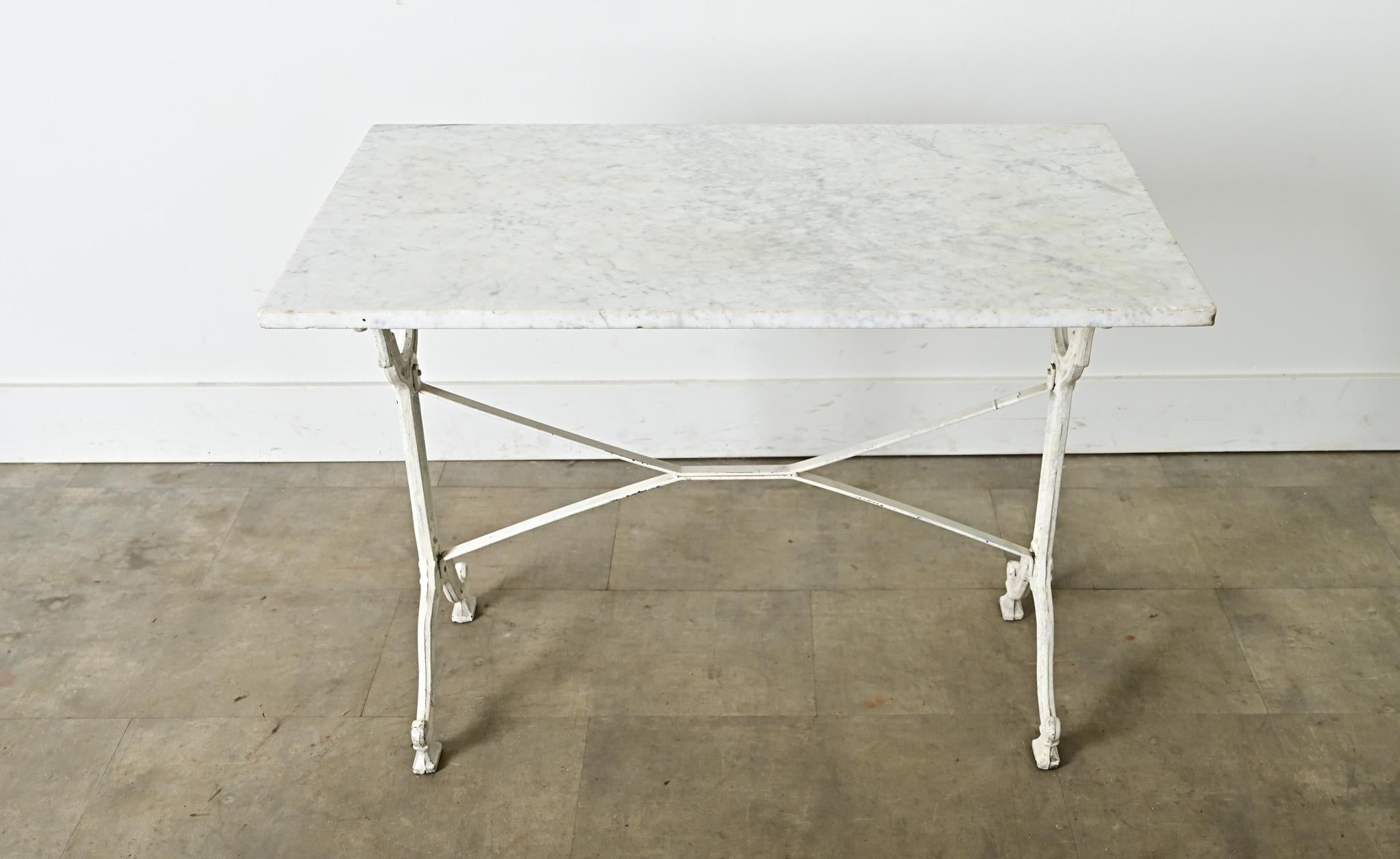 A turn of the century (circa 1900) French bistro table of Beaux Arts/Art Nouveau “fin de siècle” period details in the painted-white cast iron base. The white marble top has fine gray veining, etched and clouded on the surface from over a century of