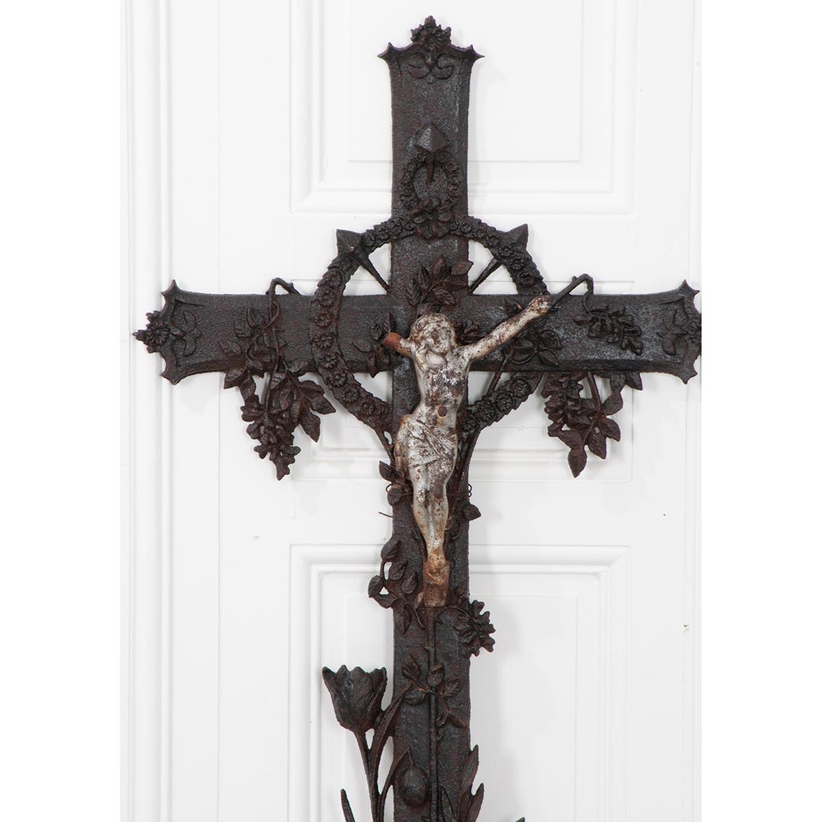 This is a French 19th century cast iron cross with a crucifix. It uses flowers as its decorative motif. These crosses were often used at a grave site or in a field of crops.
