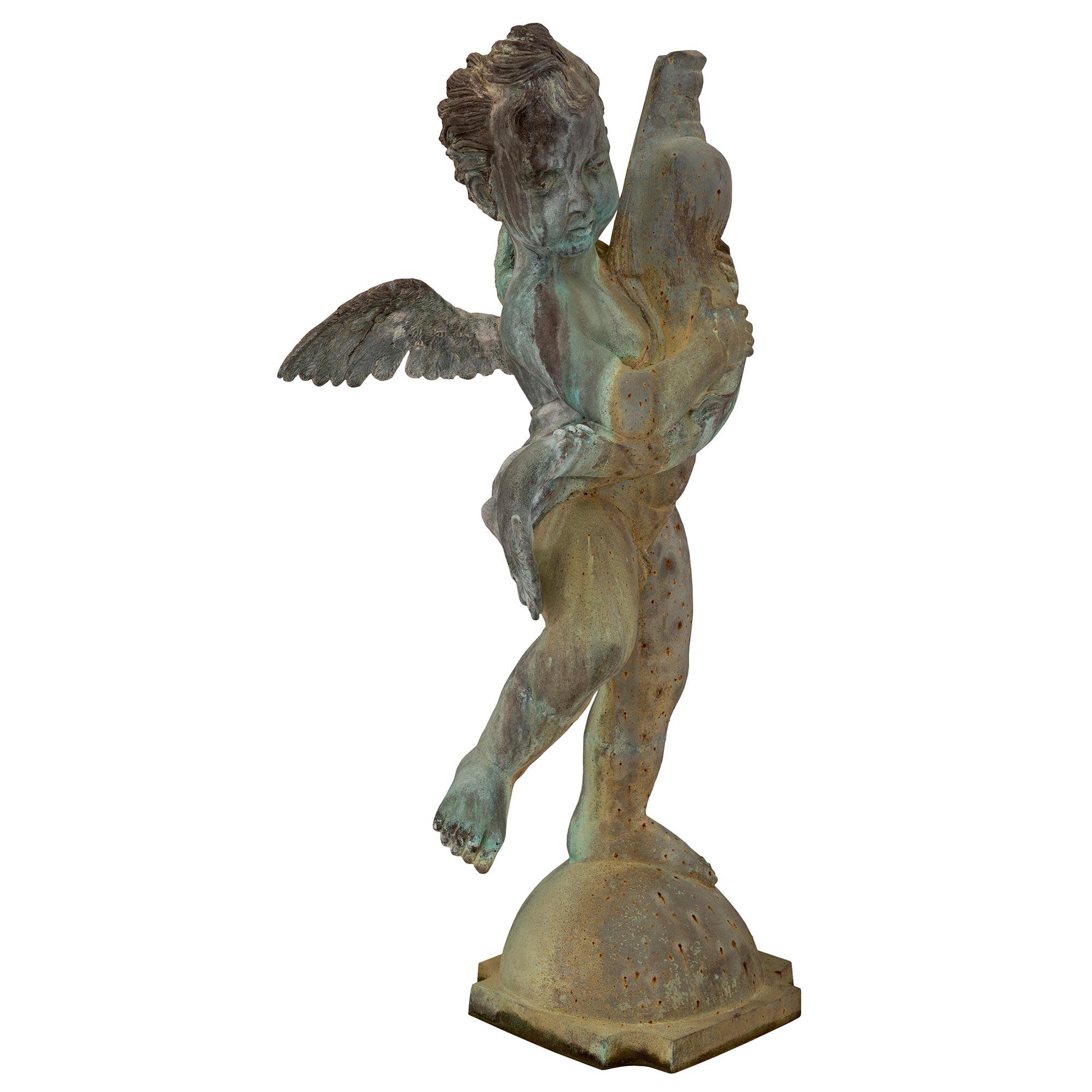 A beautiful and extremely charming French 19th century cast iron fountain of a young boy holding a dolphin. The fountain is raised by a square base with concave corners and an elegant dome shaped support. The charming young boy displays finely