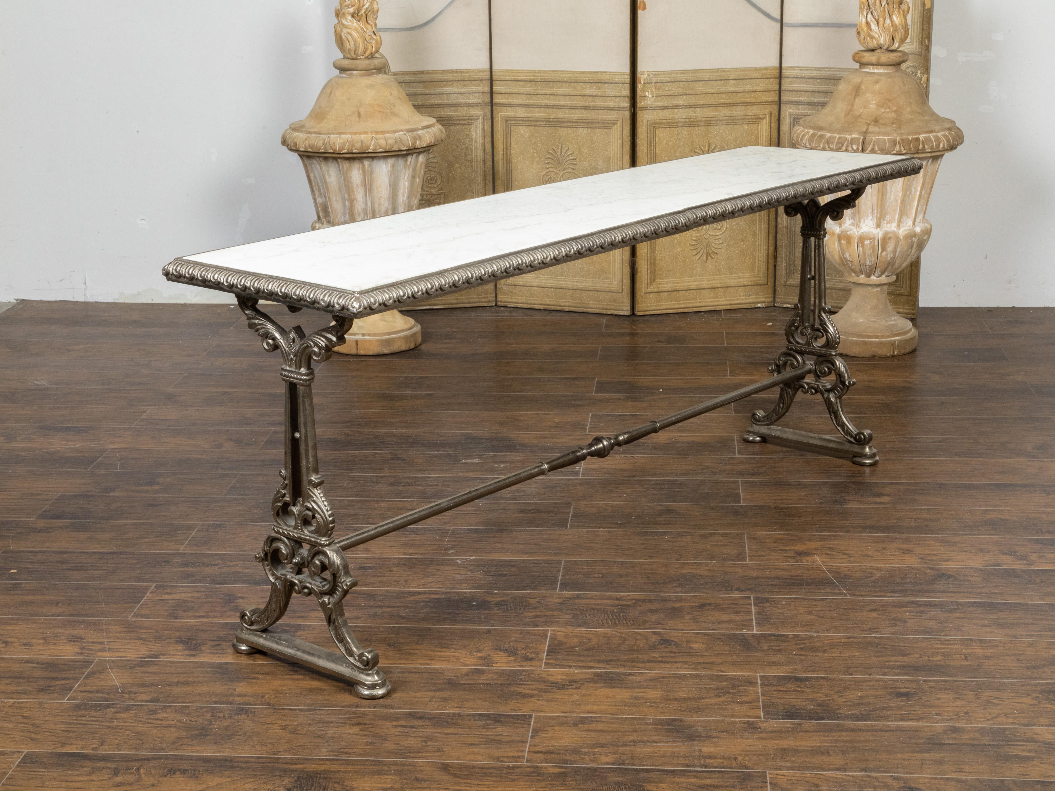 A French cast iron pastry console table from the 19th century, with white marble top, decorative motifs on the edges and trestle base accented with scrolling foliage. Created in France during the 19th century, this long and narrow pastry table will