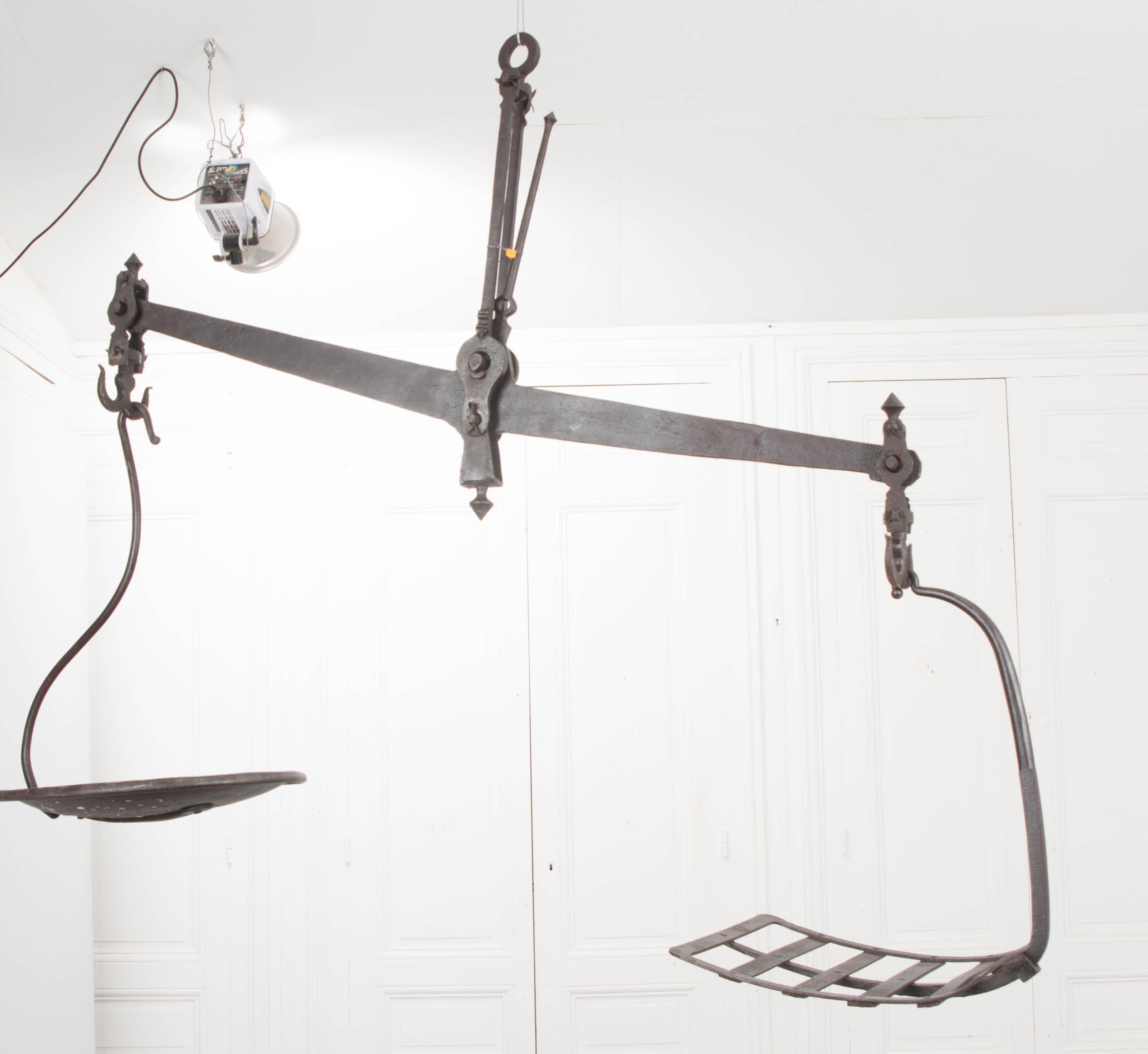 A massive 19th century hanging cast iron produce scale, circa 1860, from France which would have been used for weighing produce or meat in a warehouse or a large farmer's market. A series of weights would be place into the circular side while the