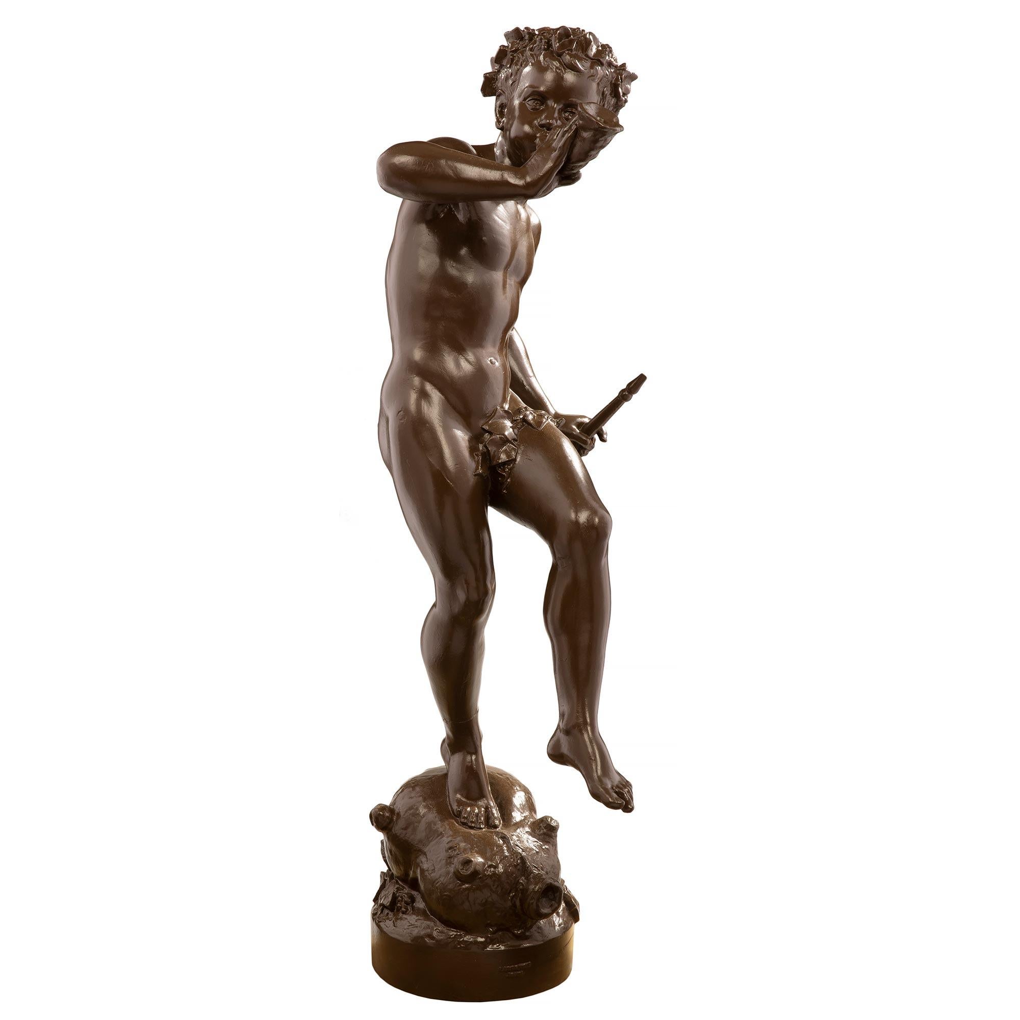 A charming and highly detailed French 19th century cast iron statue of a young boy playing the horn and holding a flute, signed 'A. DURENNE, Paris'. The statue is raised by a circular base and is standing on a bagpipe. The whimsical and joyous boy