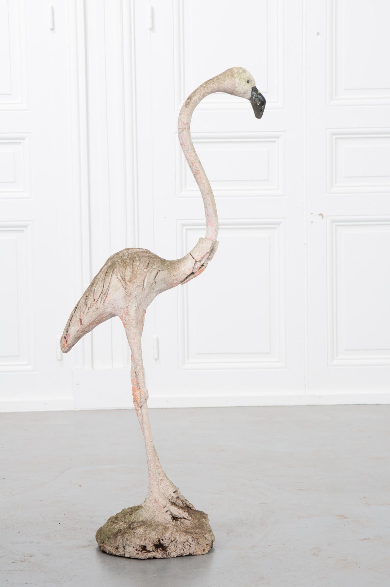 Tall flamingo of metal with cast stone. Seems the flamingo was once painted pink and has lost its color over time due to exposure. Missing part of his neck but still looking great for its age.