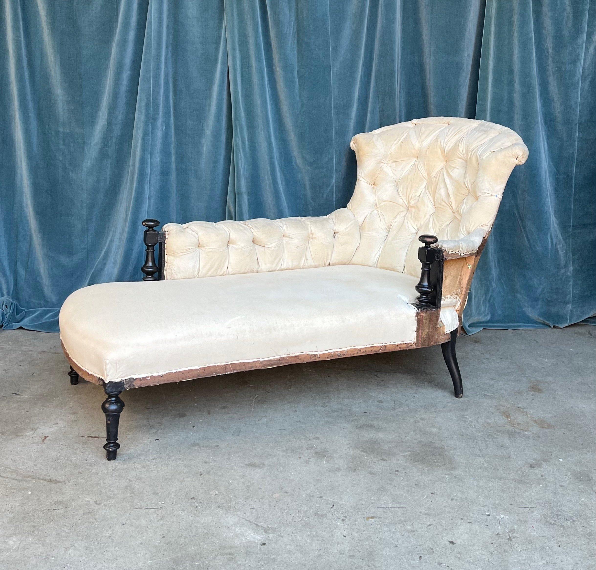 Classic French 19th century Napoleon III tufted chaise lounge with exposed wooden details on the arms. The chaise has been stripped down to the muslin and is ready to be upholstered. The asymmetrical chaise is “right- armed” and the front has a