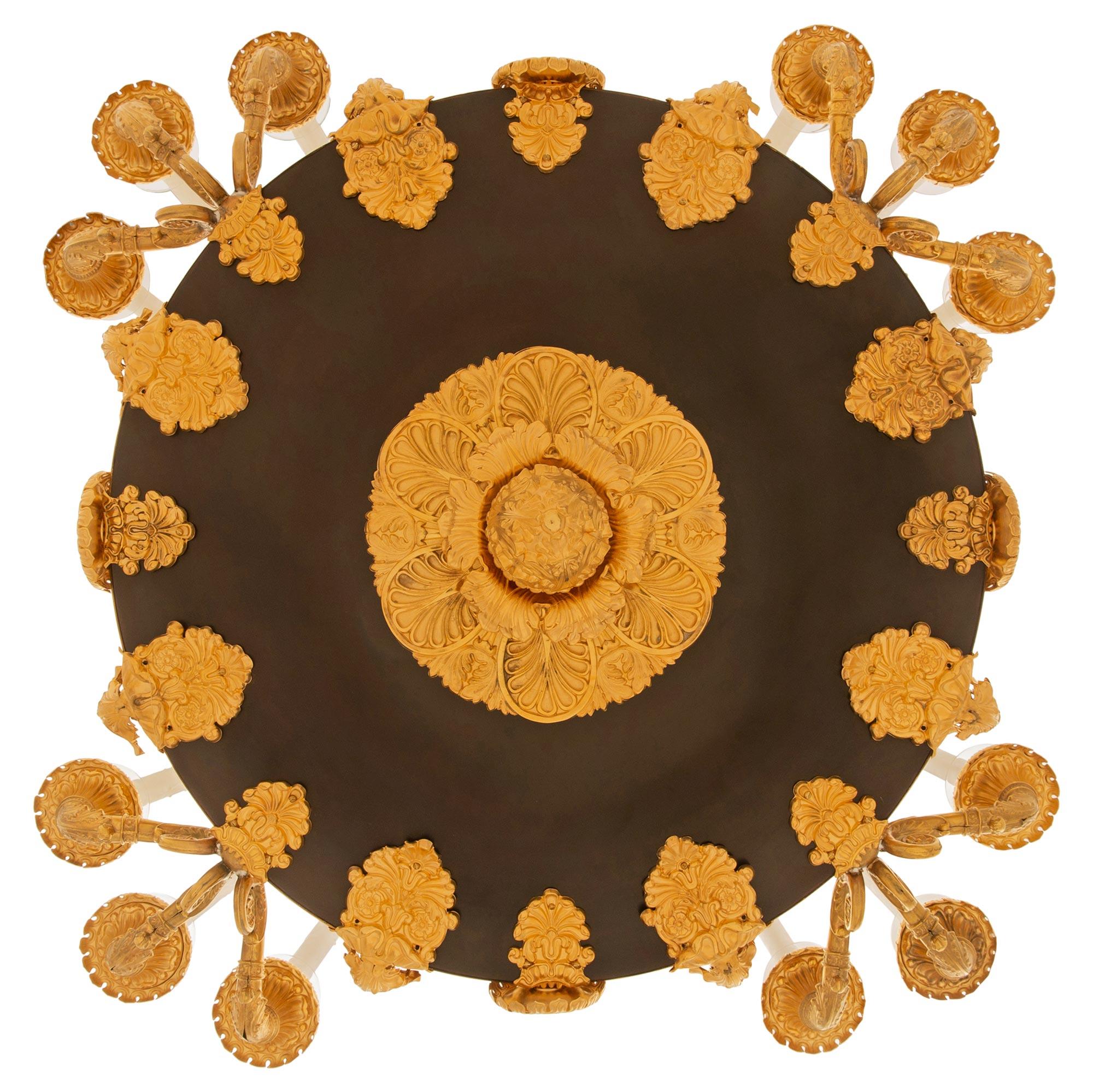 Lustre en bronze patiné et métal doré d'époque Charles X, du XIXe siècle, d'une taille impressionnante et de grande envergure. Le lustre à douze branches est centré par une ravissante finale en métal doré sous le corps en bronze patiné, entouré de