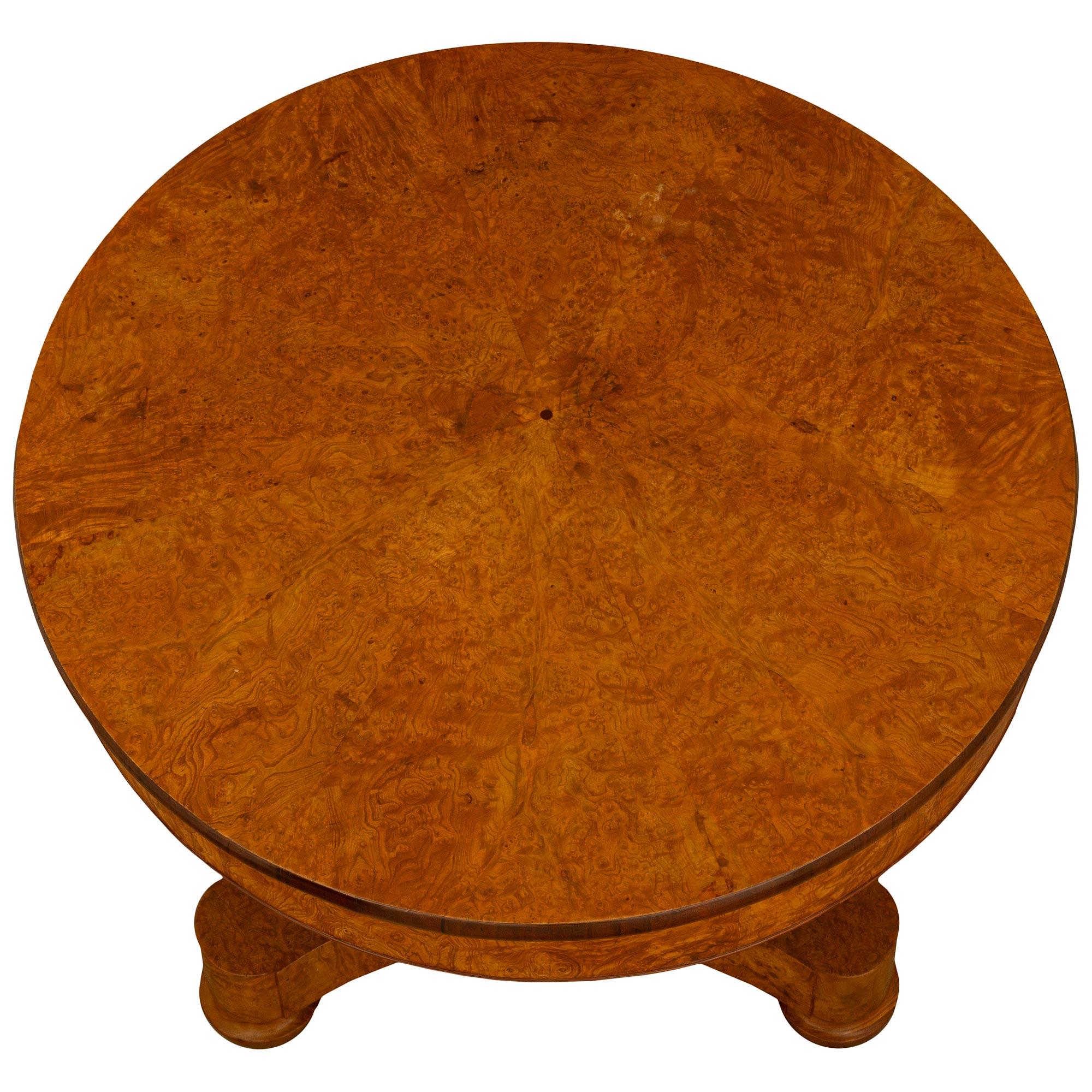 A very attractive French 19th century Charles X st. burl Walnut center table. The table is raised on bun feet below the handsome triangular base with concave sides. Above is the elegant central tapering triangular support below the circular top. At