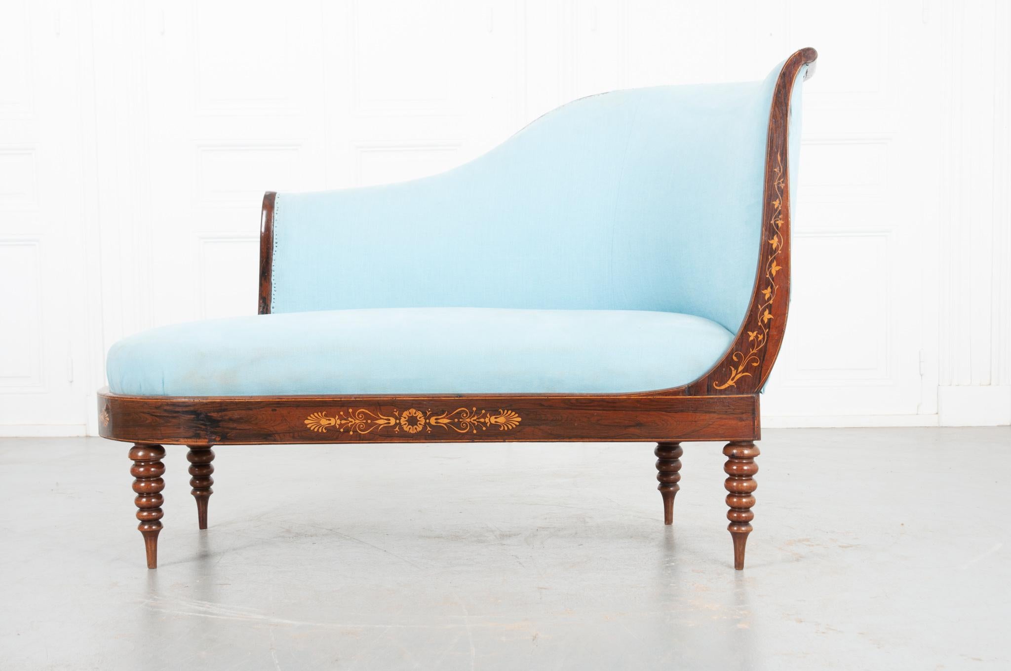 This elegant settee is upholstered with a stunning blue fabric that brilliantly contrasts with the dark wood frame. The whole is supported by deeply turned legs and elevates the piece 10” from the ground. The curved apron has a beautiful floral