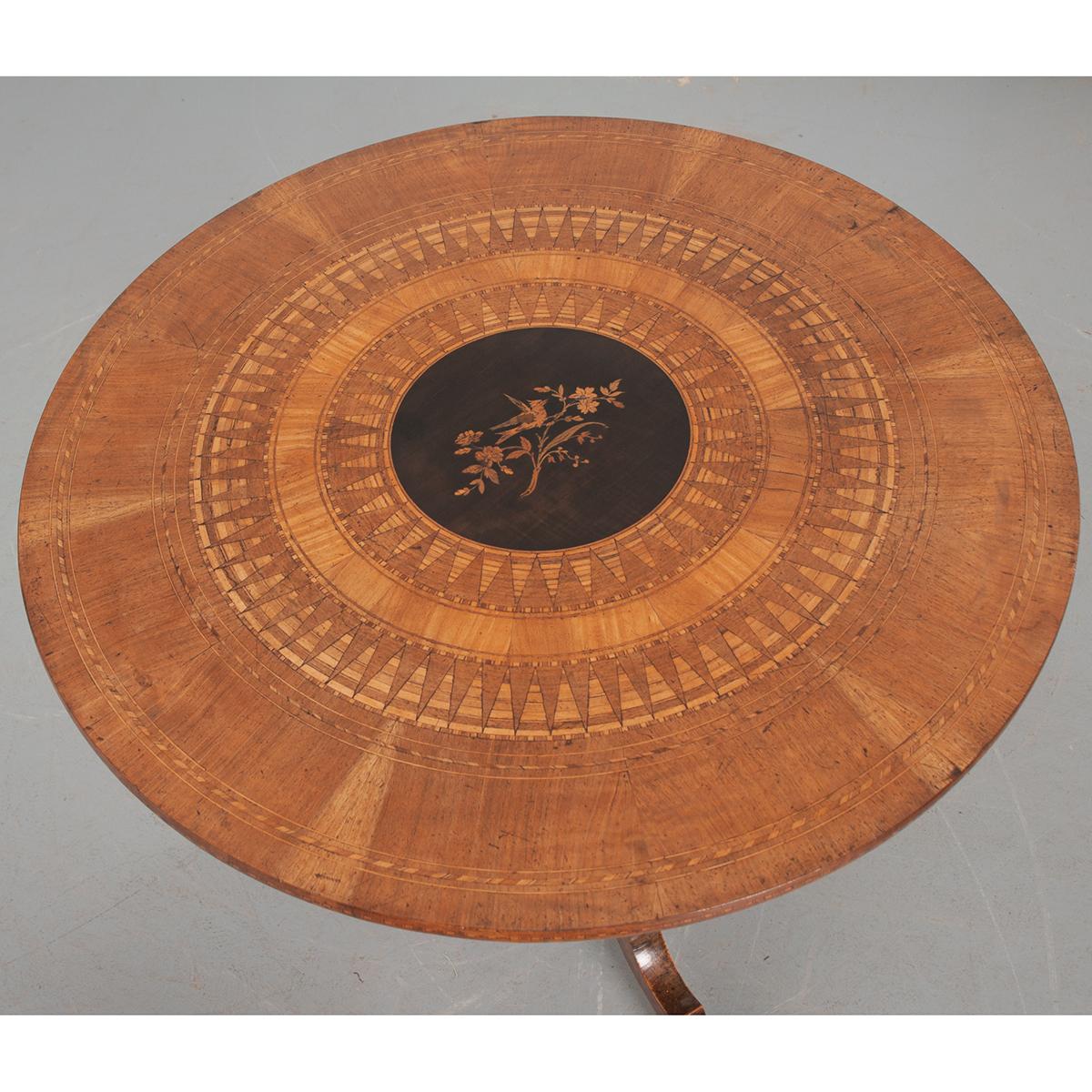 This French 19th century tea table is quite nice. It is Charles X style and circa 1830. It has a center medallion of ebonized wood inlaid with a bird perched on a branch of leaves and flowers. There are many concentric circles going to the edge of