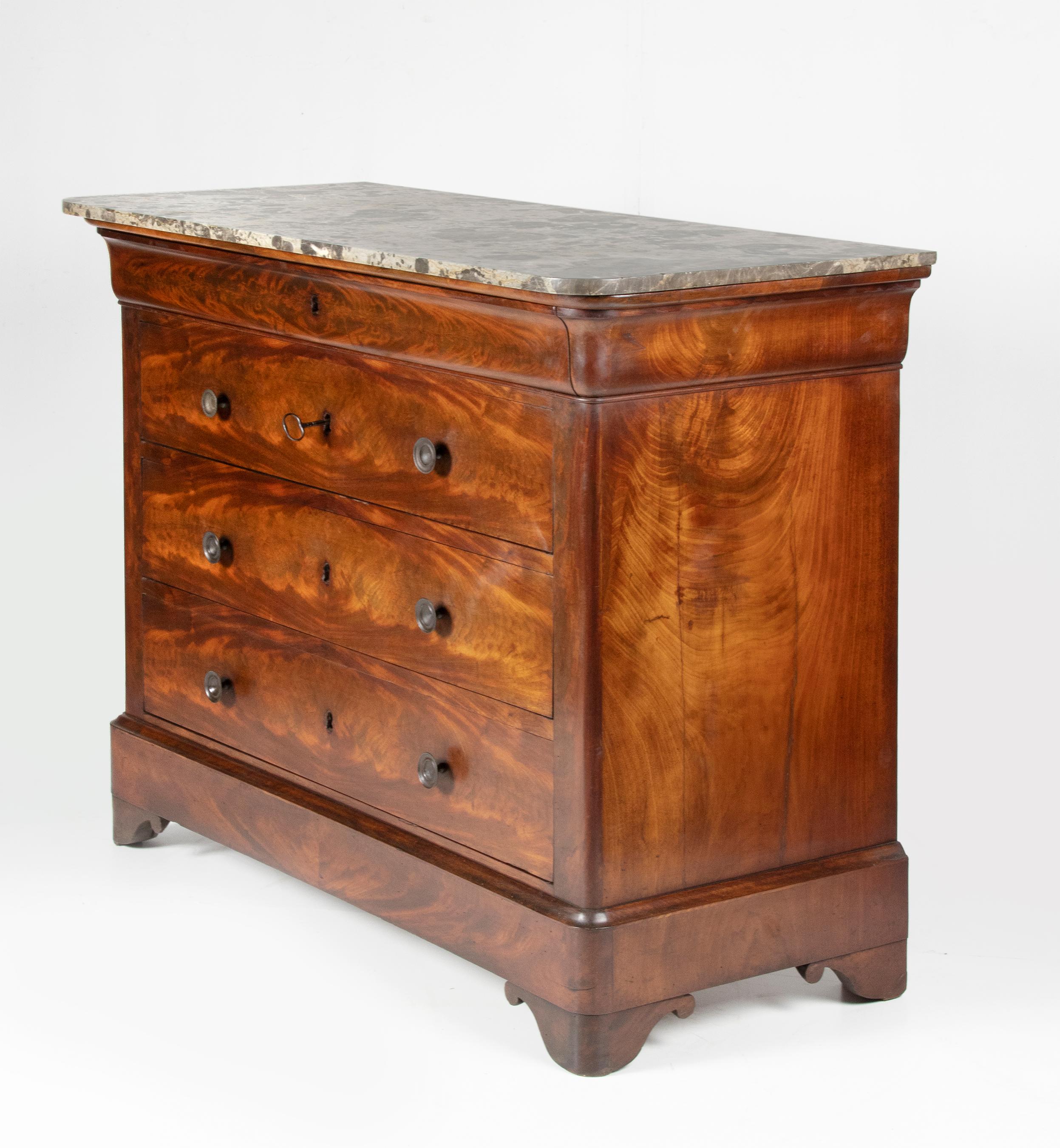 19th century French chest of drawers, commode, mahogany veneered. Louis Philippe style, with grey marble top. 
There is one key with this piece, the key fits on all for drawers.
The back of the furniture has many small woodworm holes. But the