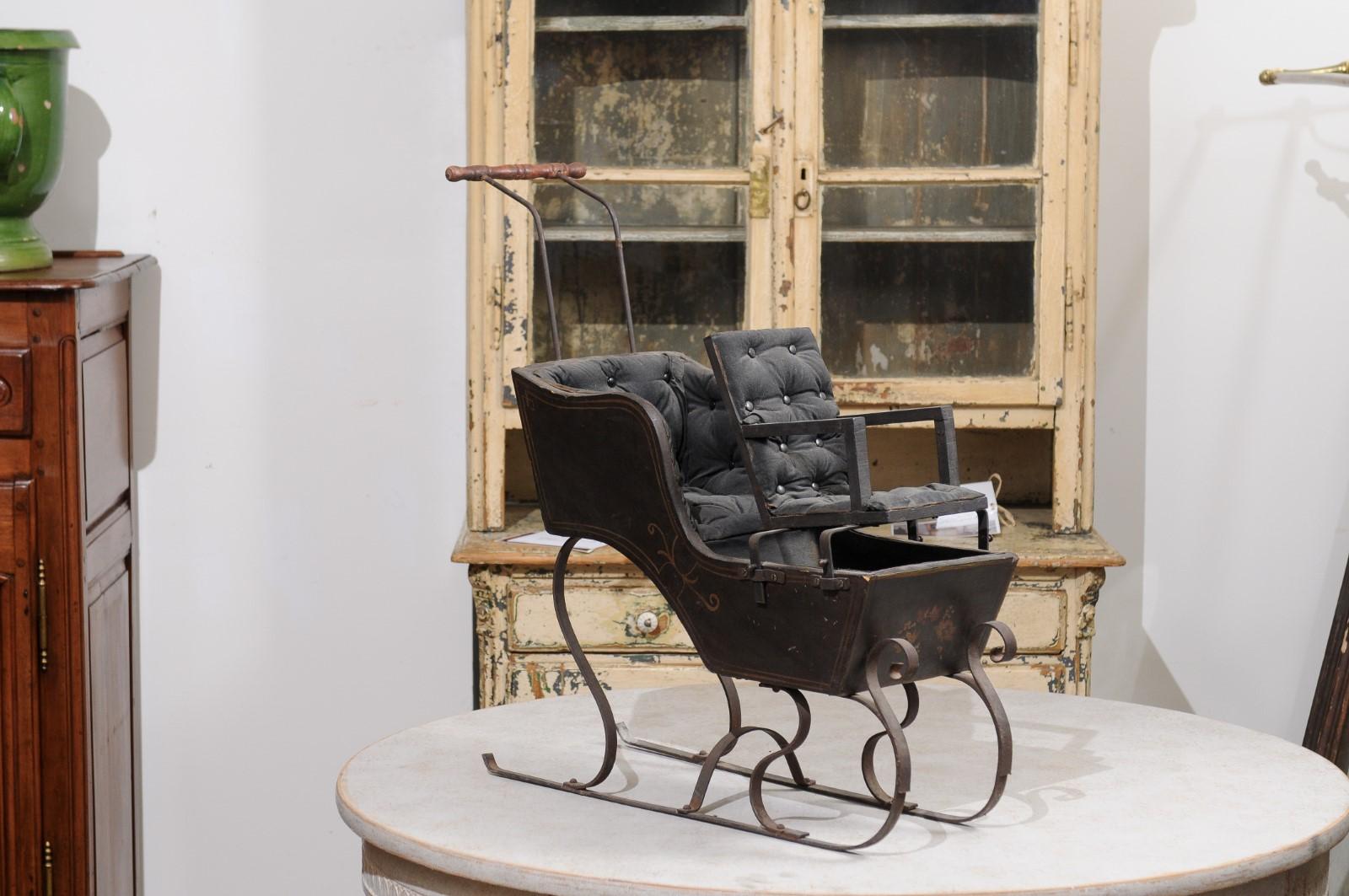 A French child's sleigh from the 19th century, with tufted upholstery and floral painted décor. Created in France during the 19th century, this child's sleigh charms us with its petite proportions and graceful lines. Boasting a dark patina, the