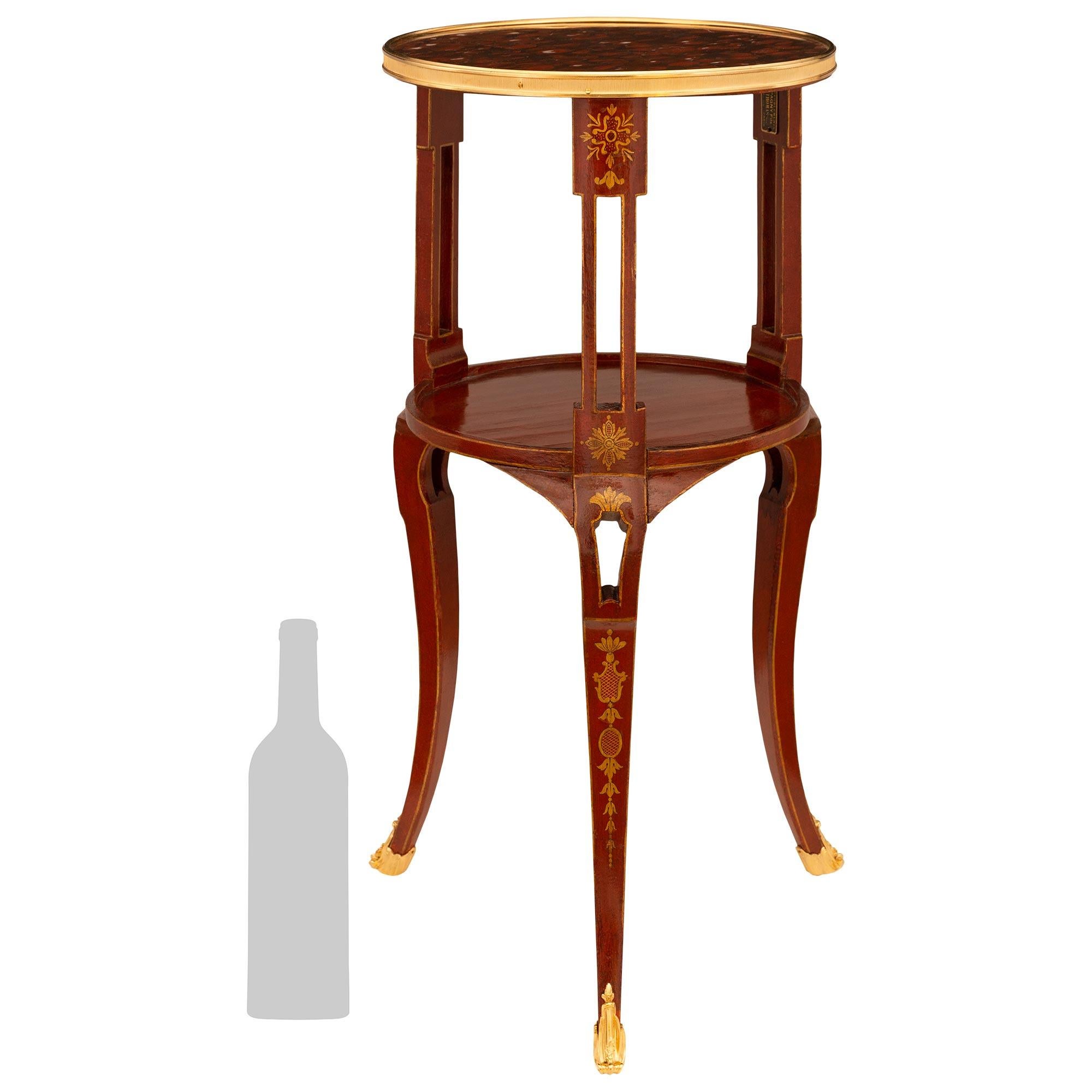 Très belle table d'appoint en bois laqué rouge, bois patiné, bronze doré et marbre rouge griotte. Cette impressionnante table d'appoint repose sur trois pieds cabriole carrés et effilés laqués rouge, dont les panneaux avant sont ornés de motifs