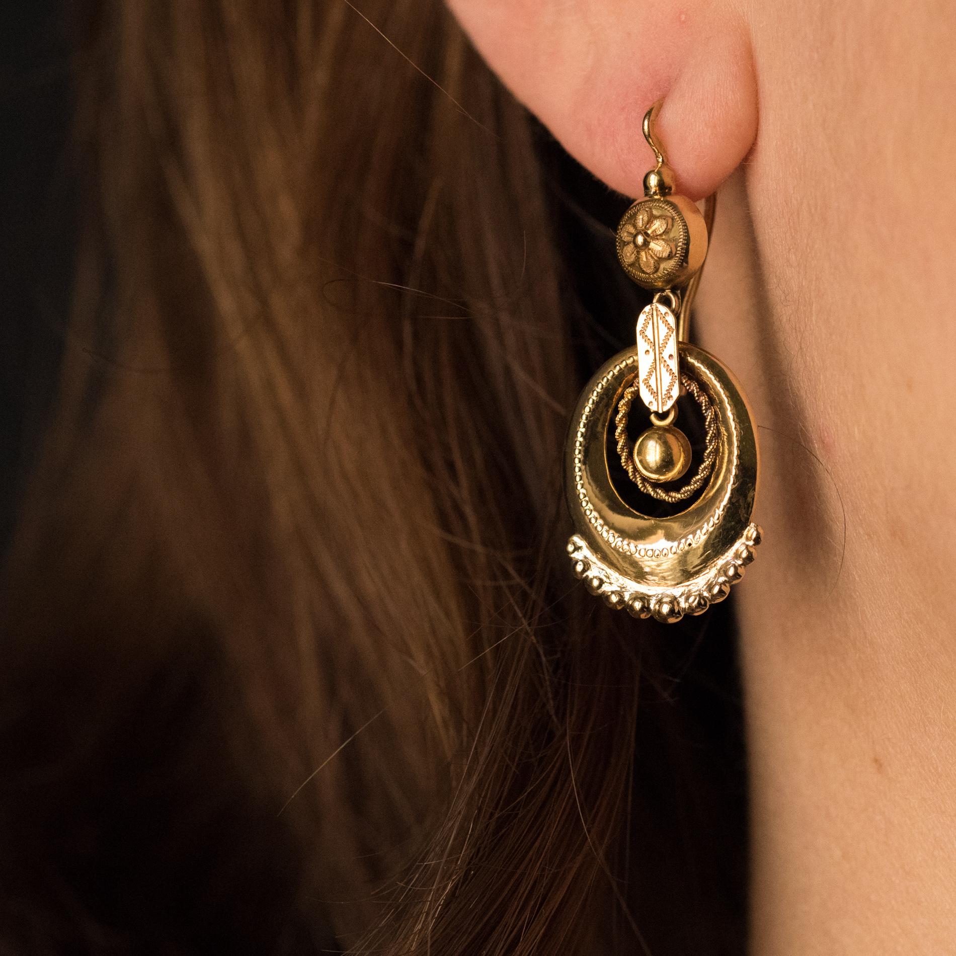 Earrings in 18 karats yellow gold, eagle's head hallmark.
Lovely antique earrings, they are composed of a half-pearl in chiseled gold that supports in pendent an oval pattern chiseled and beaded on the bottom, a gold cord and a small pearl of gold,
