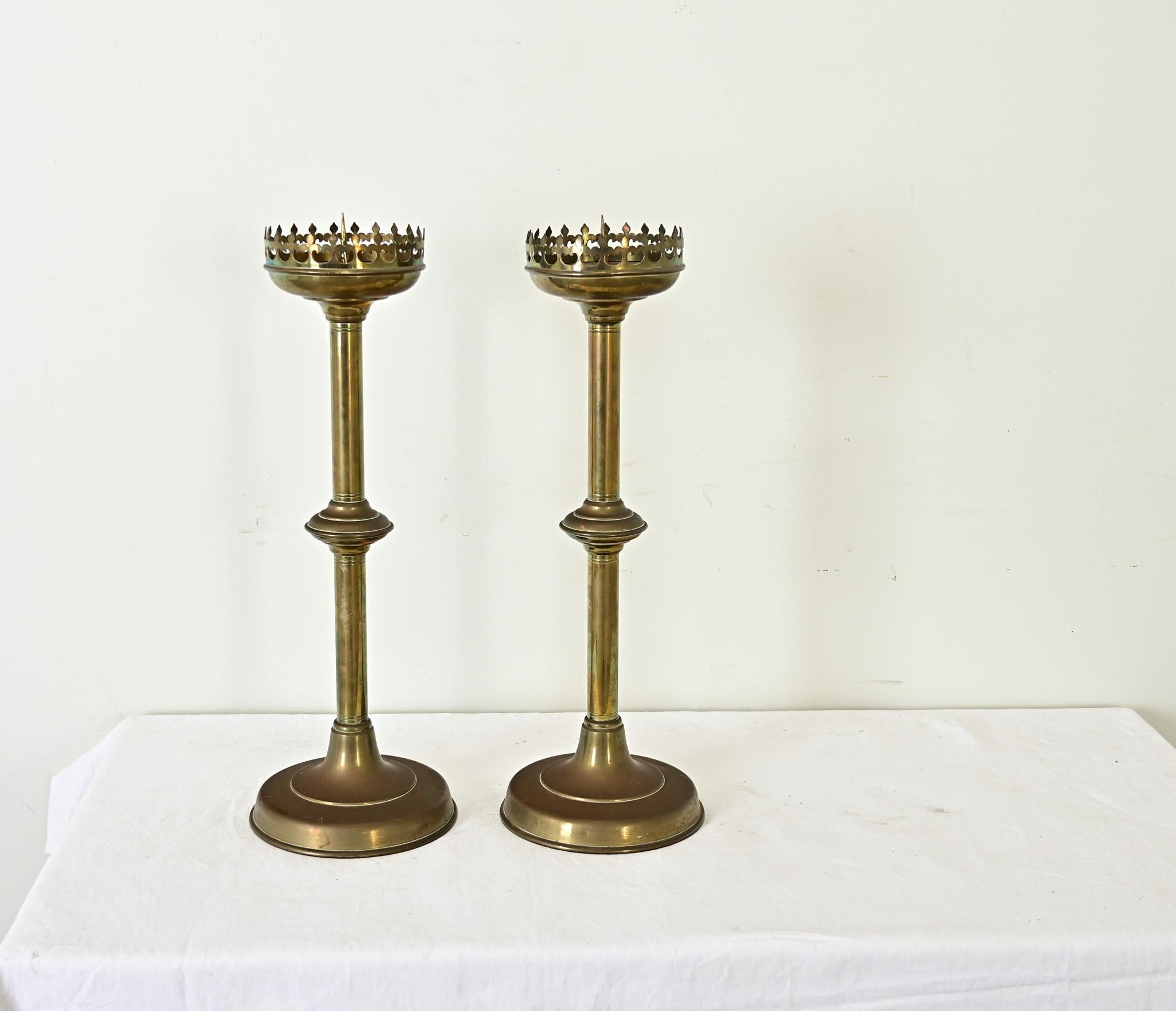 Un imponente par de candelabros de altar franceses de latón del siglo XIX procedentes de una catedral o iglesia. El centro de cada bobeche está provisto de una espiga, rodeada por una corona de latón calada de inconfundible diseño de flor de lis.