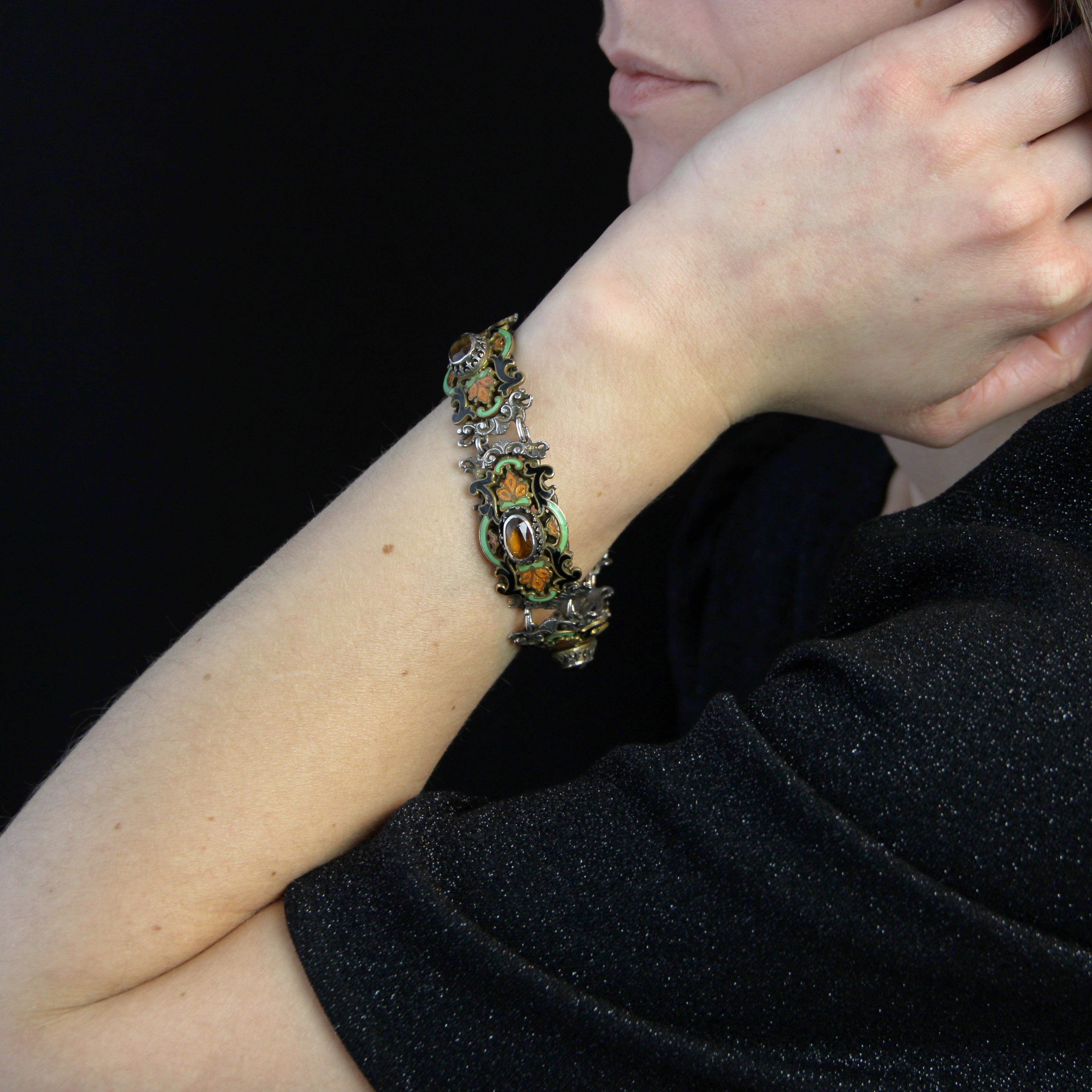 Bracelet en argent, poinçon tête de bélier.
Ce bracelet ancien présente 4 motifs rectangulaires séparés par des anneaux. Chaque motif est incurvé, percé d'arabesques et gravé de motifs végétaux. Une plaque en émail noir, vert et orange est également
