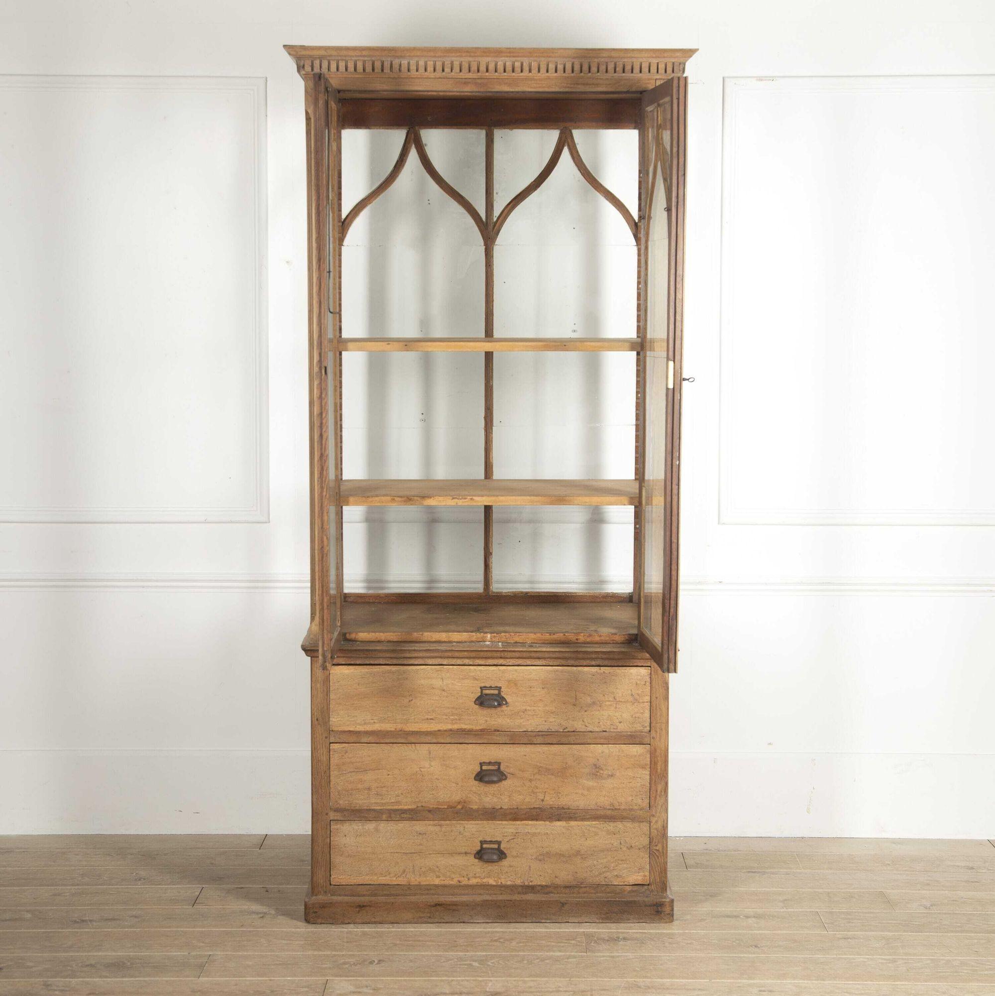 Pretty French 19th Century collectors cabinet.
This cabinet has elegant tall and slim proportions. The dentil moulded cornice sits above glazed doors with attractive arched panels which enclose shelving.
Below, the oak base offers three long