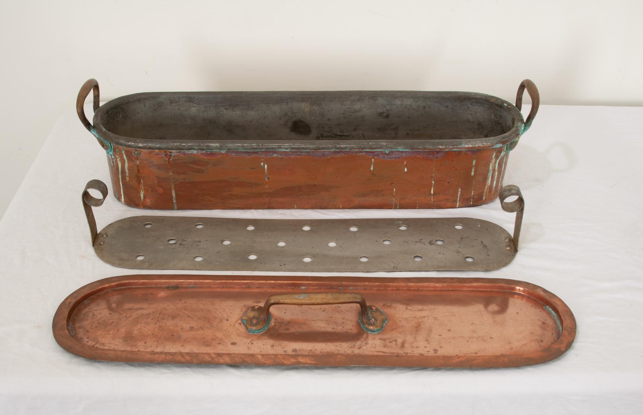 A fabulous French 19th century copper poissonniere or fish kettle. This long and extremely heavy rectangular pot was crafted of solid copper and retains its three large original handles attached with rivets and interior removable zinc grille liner.