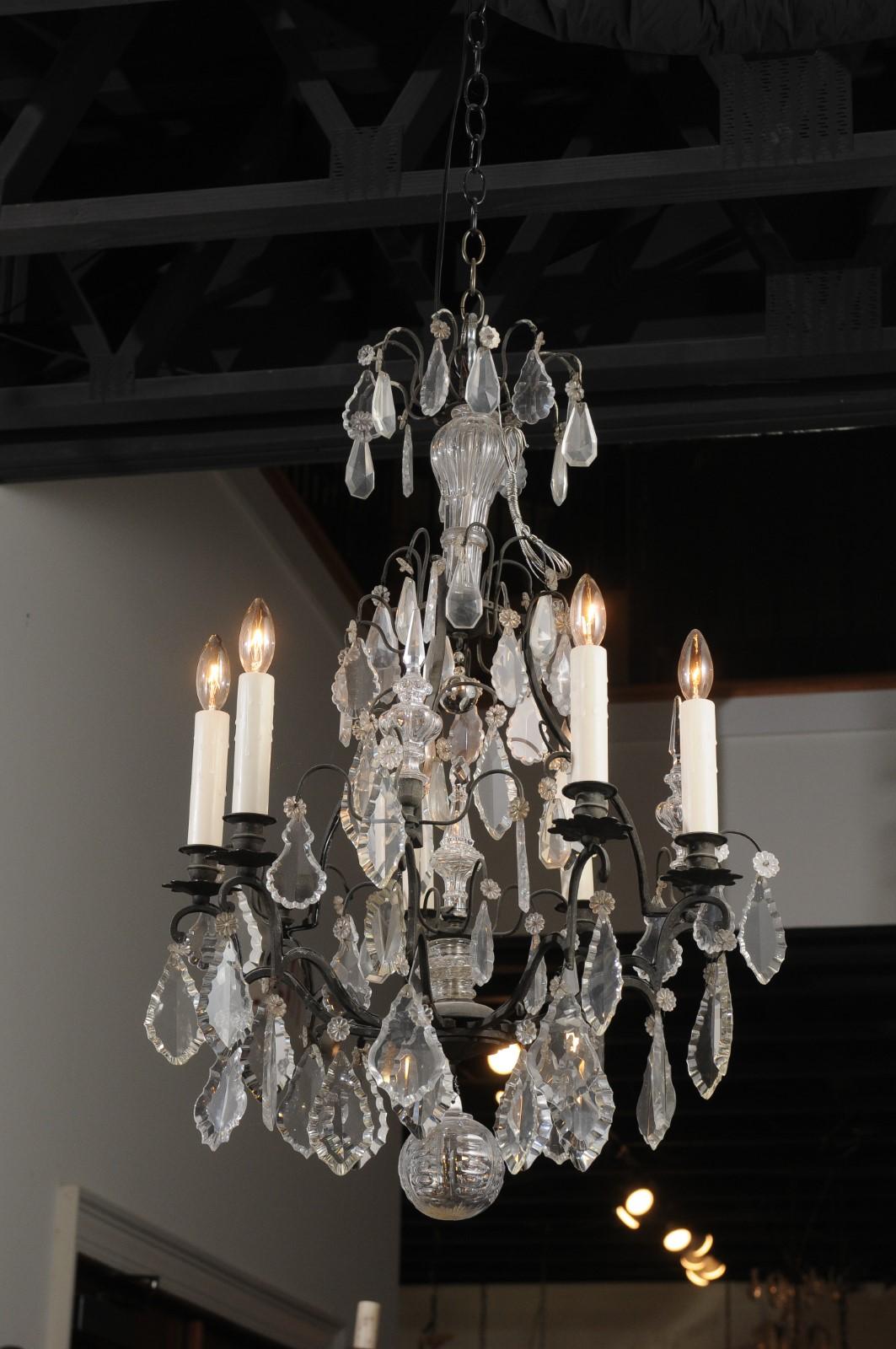 A French six-light iron and crystal chandelier from the 19th century, with pendeloques and scrolled arms. Born in France during the 19th century, this exquisite chandelier features an iron armature, accented with crystal details in the centre. Six