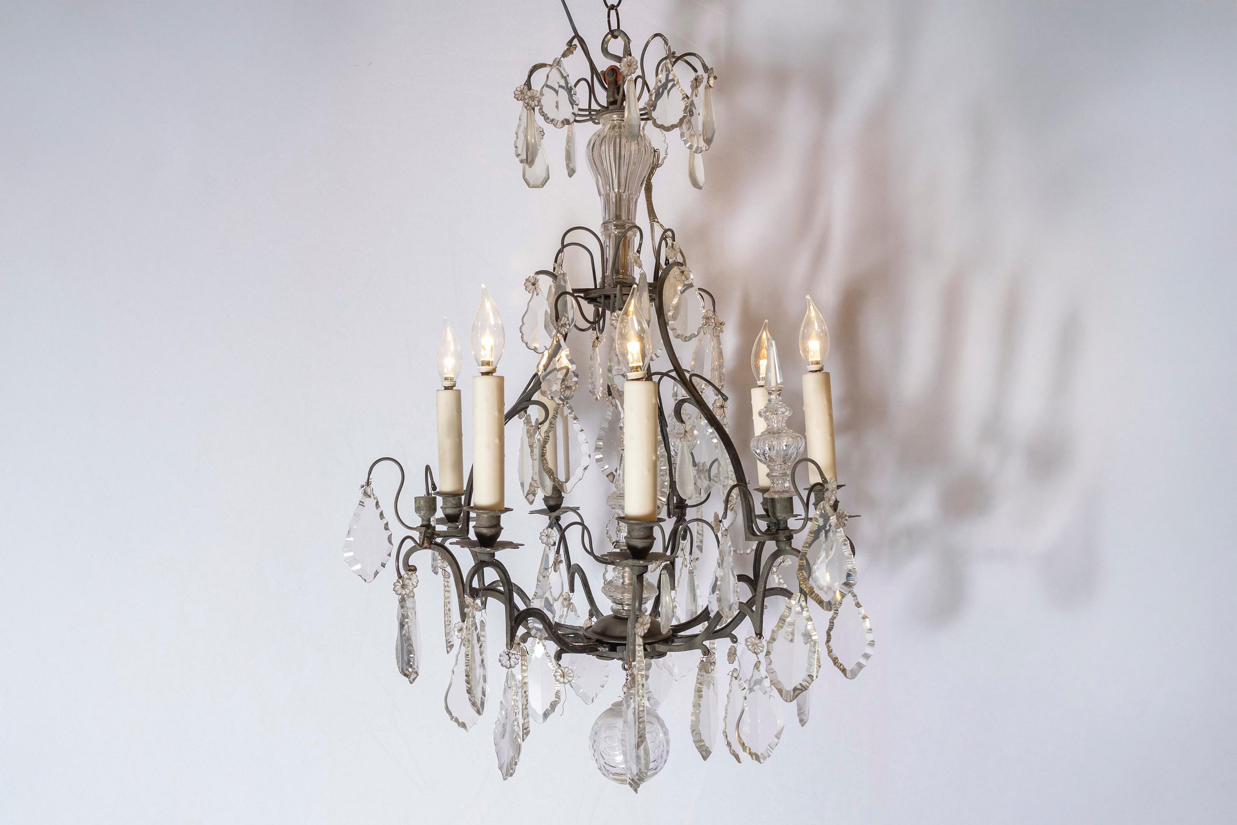 A French six-light iron and crystal chandelier from the 19th century, with pendeloques and scrolled arms. Born in France during the 19th century, this exquisite chandelier features an iron armature, accented with crystal details in the centre. Six