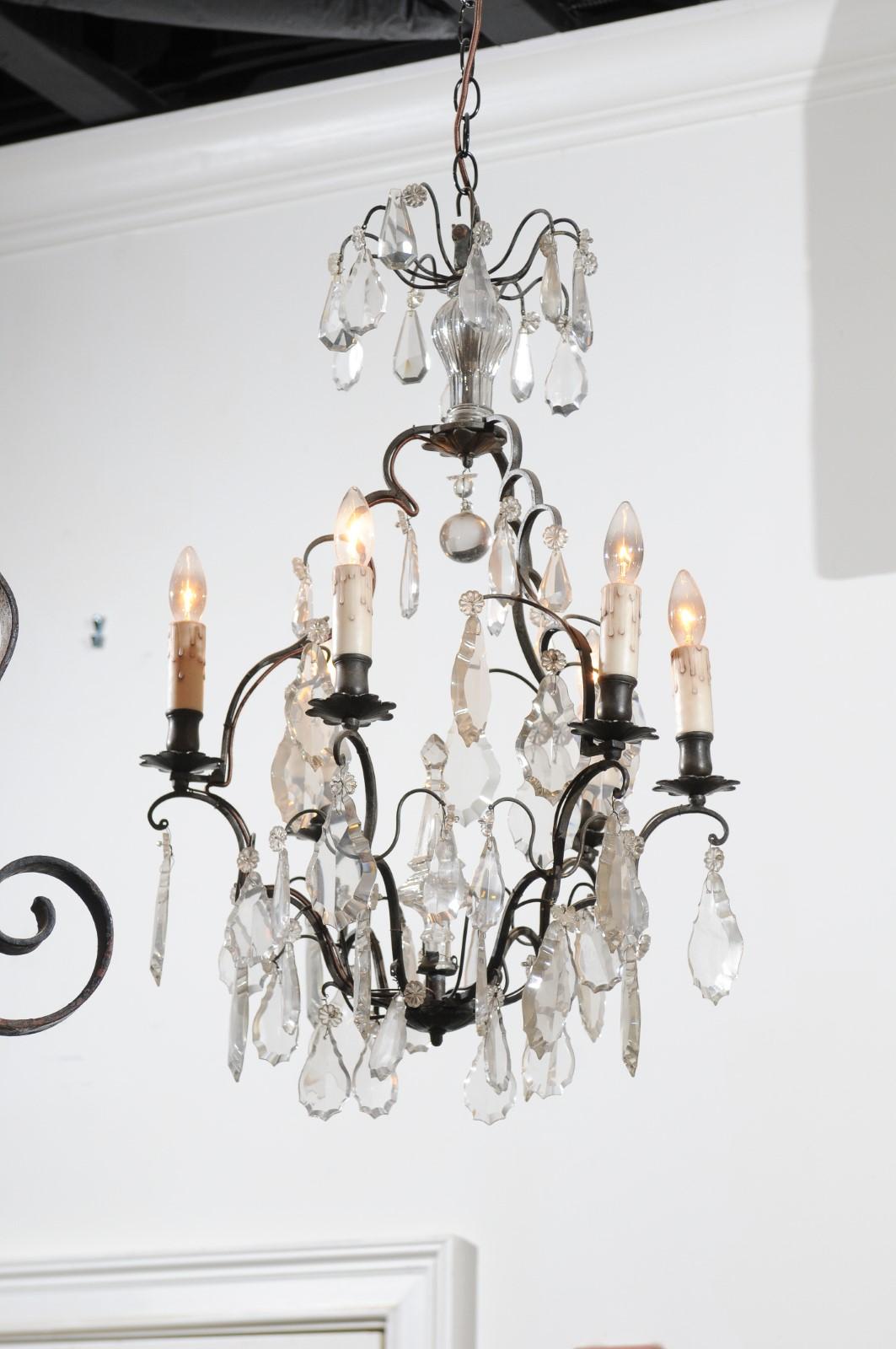 A French six-light crystal chandelier from the 19th century, with iron armature and obelisk accent. Born in France during the politically dynamic 19th century, this French chandelier features an iron scrolling armature supporting a variety of