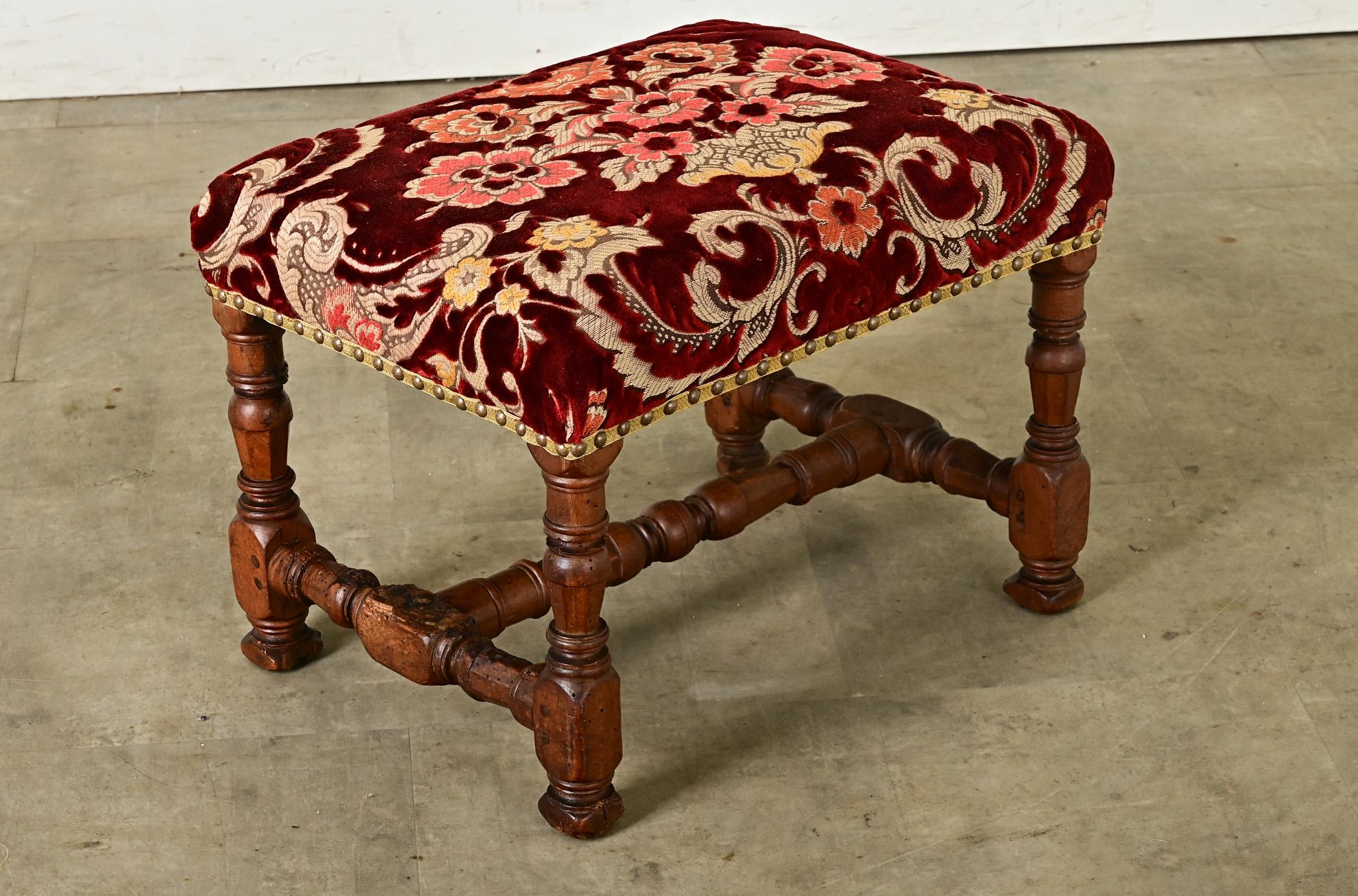 Su questo poggiapiedi francese del XIX secolo, la seduta è rivestita in lussuoso velluto di seta, tagliato e broccato in un motivo floreale a cesto di bordeaux e rosa come un raffinato damasco. Lo spesso pelo del materiale è in condizioni notevoli