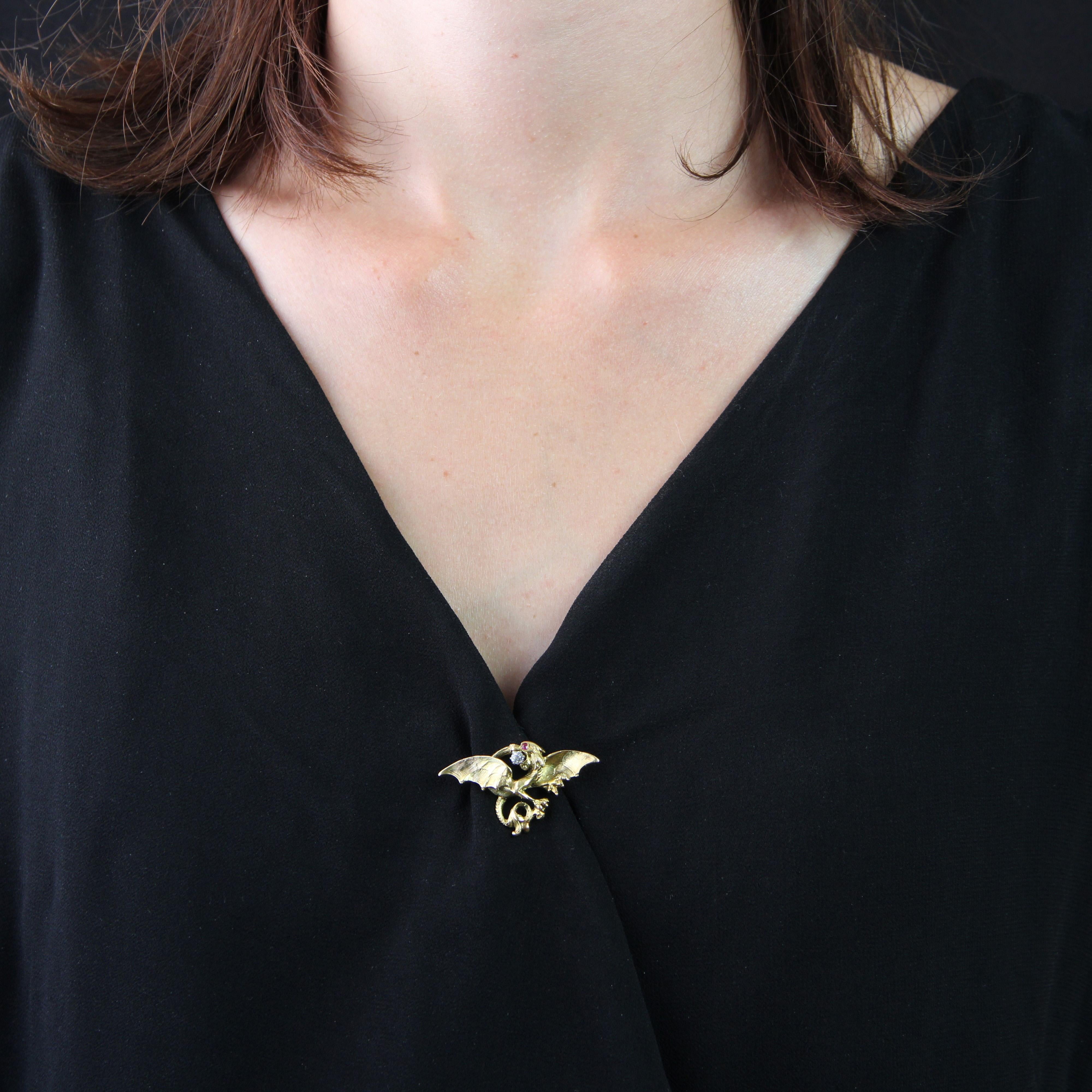 Brooch in 18 karat yellow gold, eagle head hallmark.
Magnificent antique brooch depicting a chimera with its wings spread. The creature's mouth is open, and between its fangs is an antique brilliant-cut diamond. Its eye is a small ruby. The clasp is