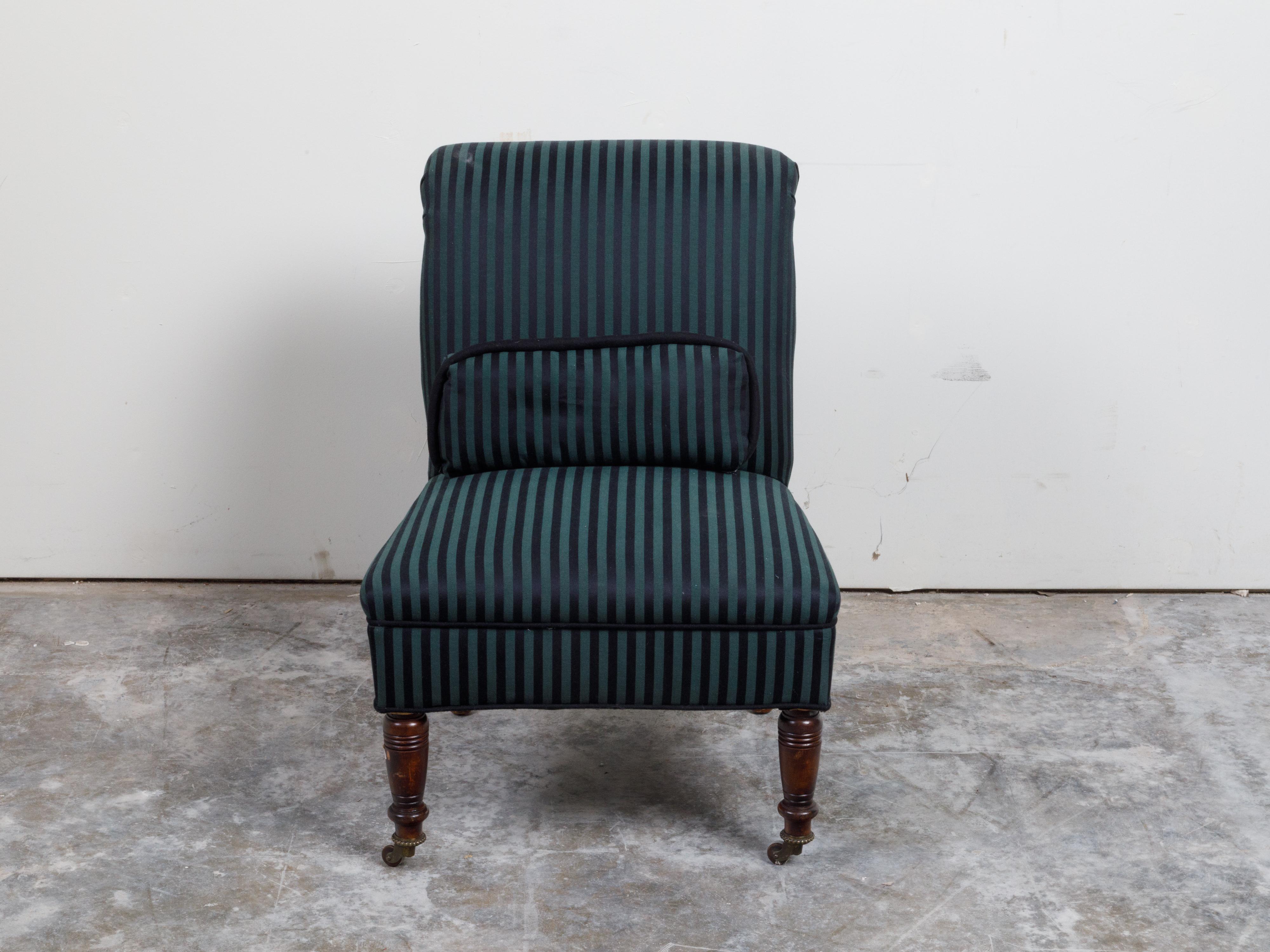 A French Directoire inspired wooden slipper chair from the 19th century, with striped upholstery and casters. Created in France during the 19th century, this slipper chair, made to be used in a bedroom to help a lady get dressed, is upholstered with