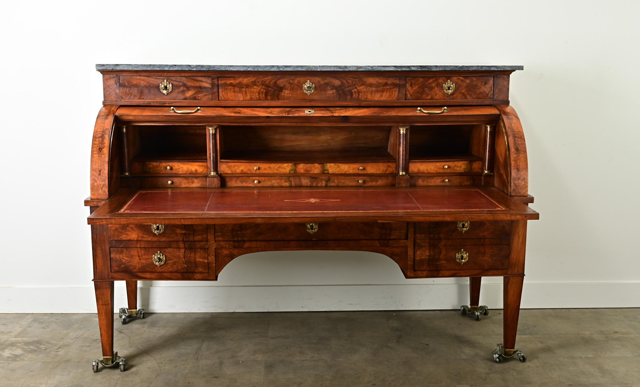 Una maestosa segretaria francese del Direttorio con piano a rotelle. Questa imponente scrivania è lunga più di due metri e alta quattro, con un piano in marmo grigio. Direttamente sotto il marmo si trovano tre cassetti con bellissimi frontali in