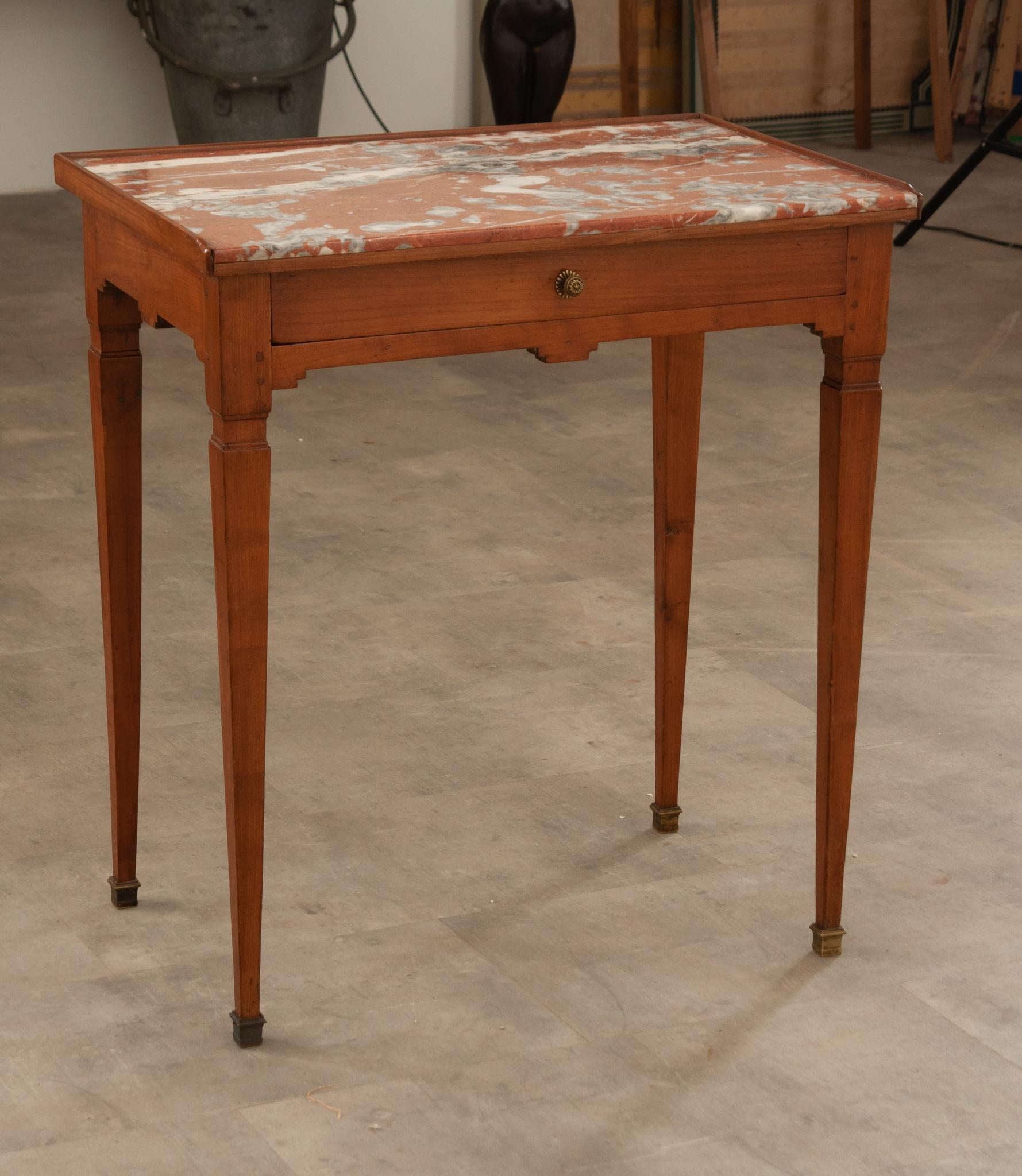 This fruitwood occasional table is topped with an inset piece of stunning red Rosso Francia marble and surrounded by a 3/4th gallery over an apron with a single drawer. The drawer contains a non-removable divider to help keep those small things