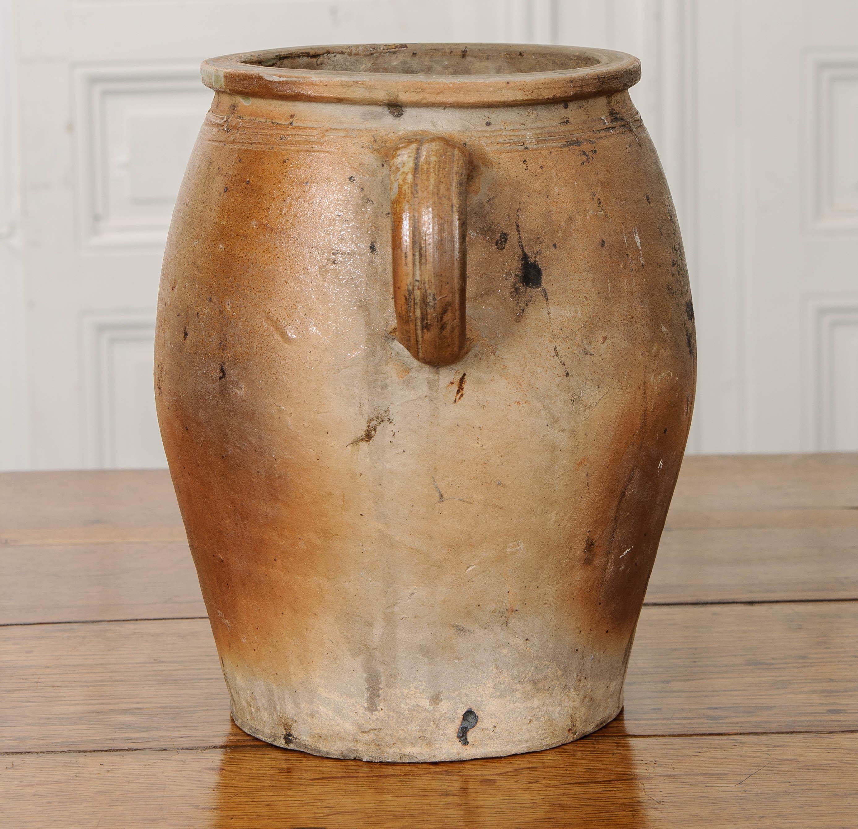 This 19th century earthenware crock is from France. Its looped handles make lifting the pot a little easier, and the decorative banding found above them gives it a distinct style. Every ceramic pot will differ slightly, as they are all thrown by