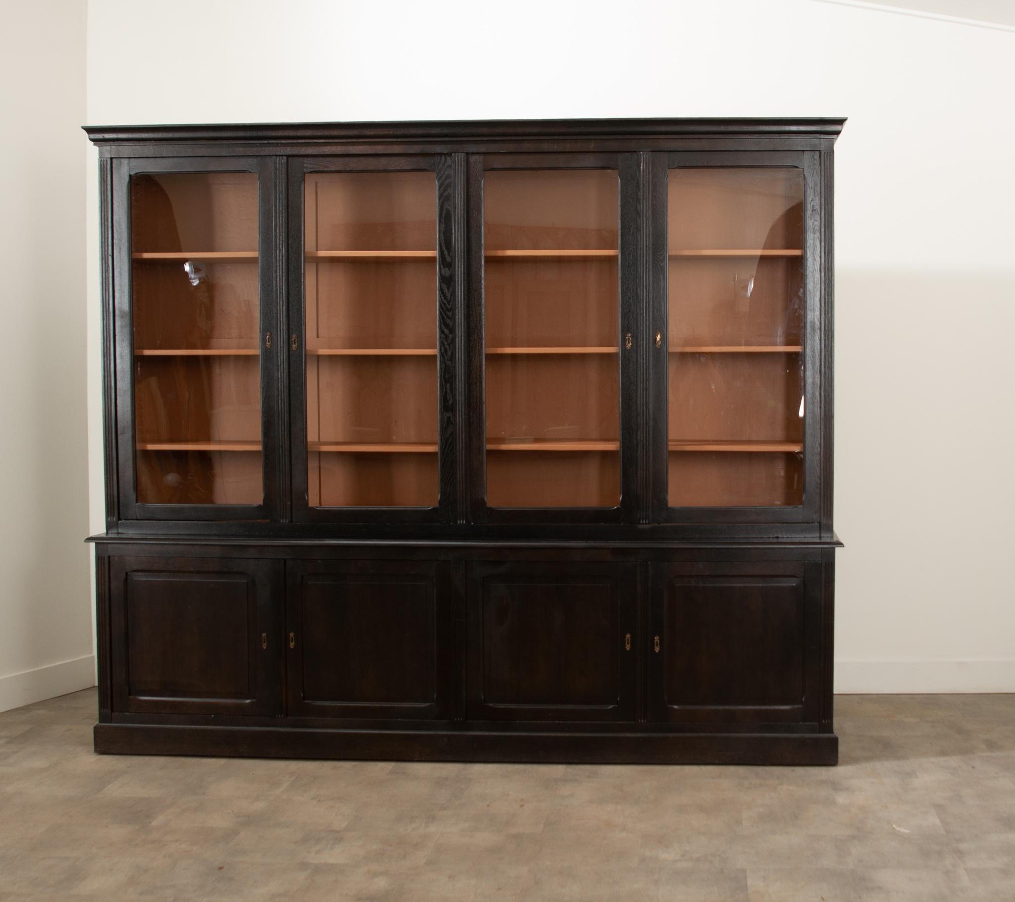 A beautiful and sizable French 19th century bibliotheque. The four trimmed glass front, locking and latching upper doors close before three saw-tooth adjustable shelves. The interior is painted a gorgeous dusty terracotta color by Benjamin Moore